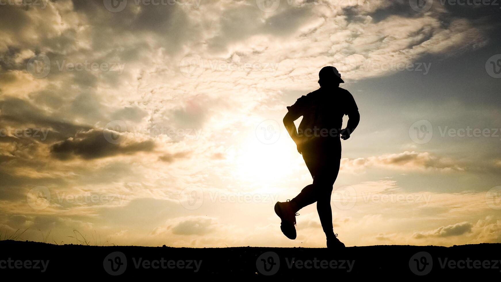 Silhouette of a Man Running at Sunset with Dramatic Cloudy Sky in the Background photo