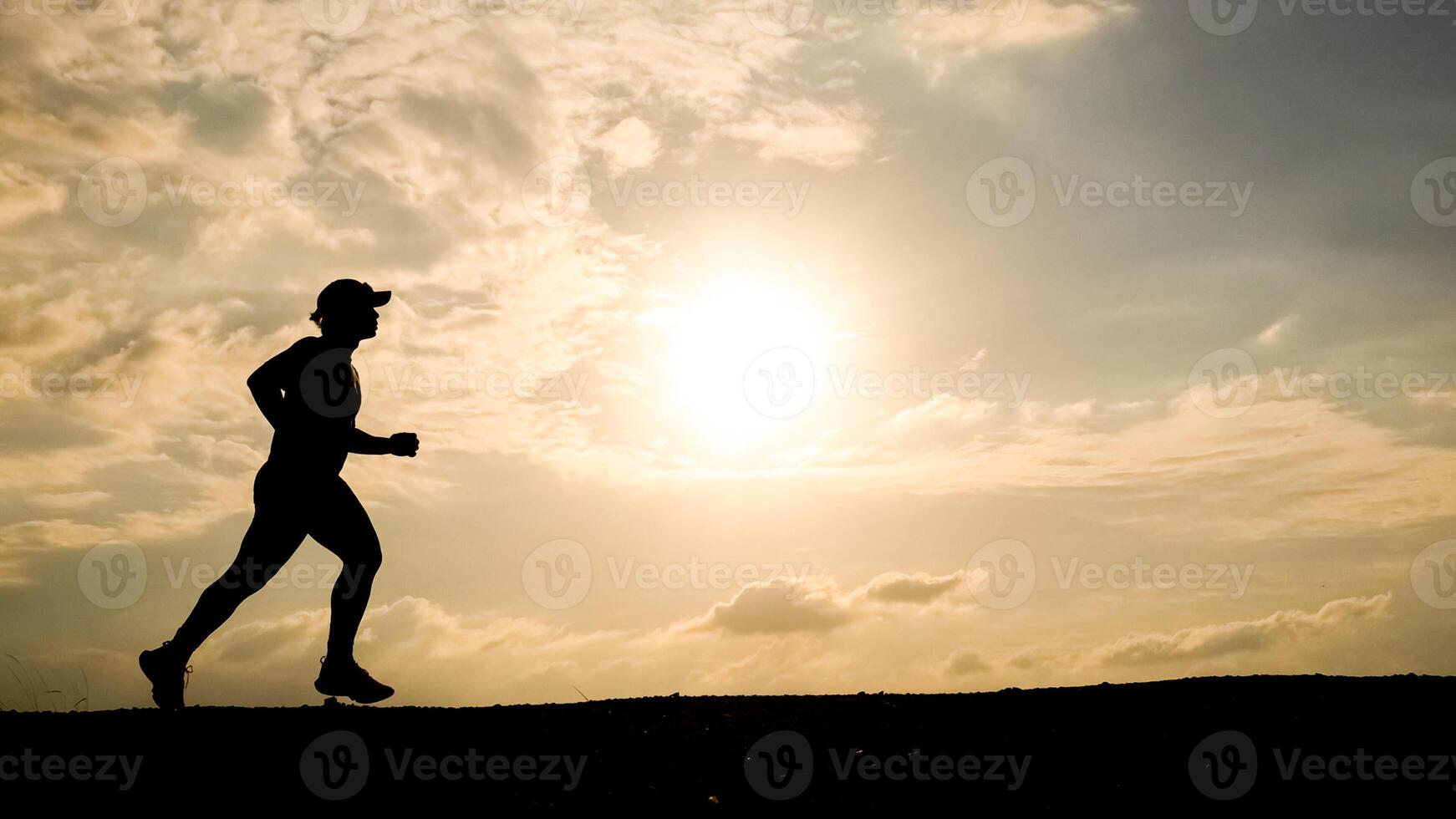 Silhouette of a Person Running at Sunset with Dramatic Sky and Clouds in the Background photo