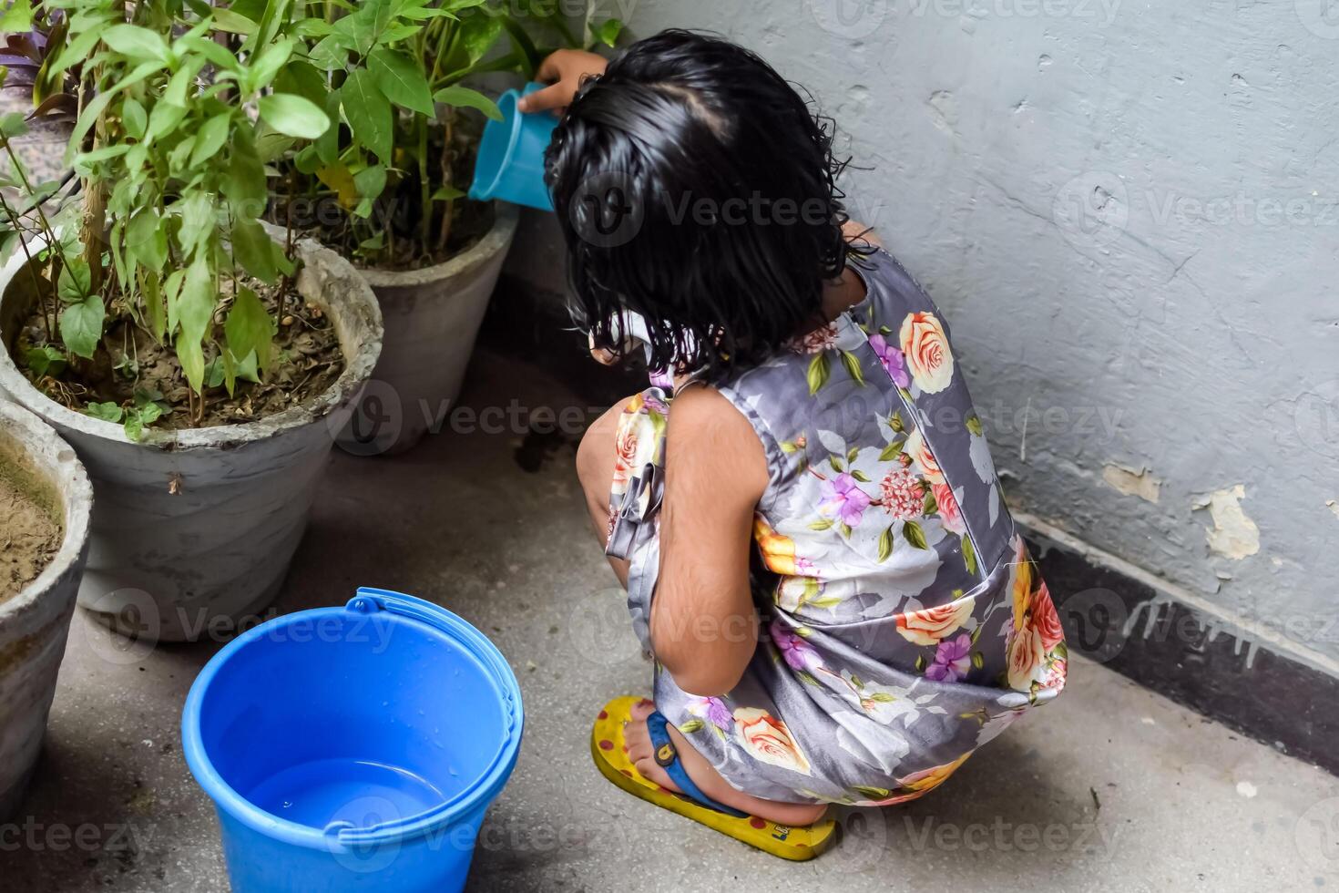 Cute 5 year old Asian little girl is watering the plant in the pots located at house balcony, Love of sweet little girl for the mother nature during watering into plants, Kid Planting photo