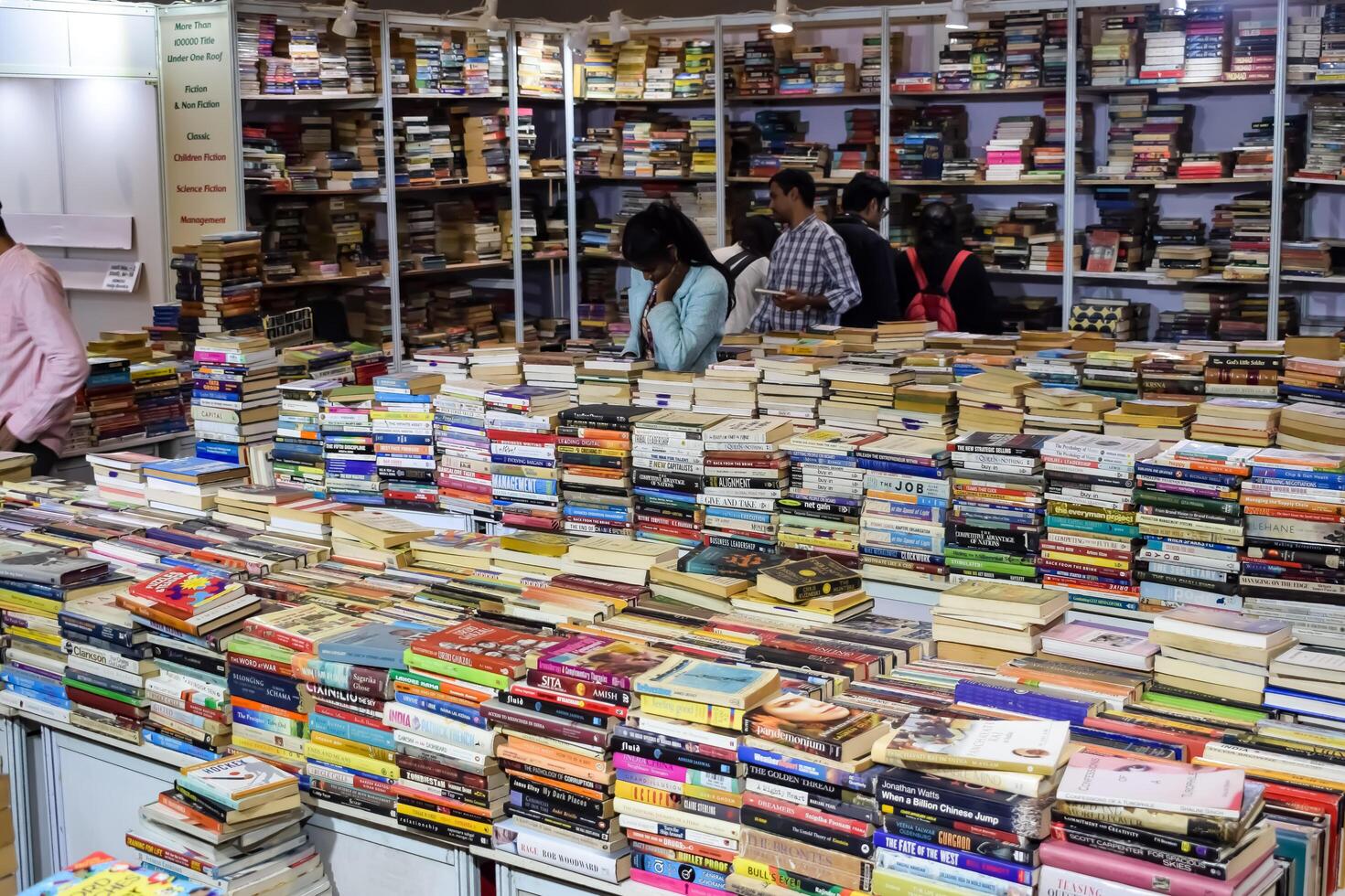 Delhi, India, July 17 2024 - Various age group people reading variety of Books on shelf inside a book-stall at Delhi International Book Fair, Books in Annual Book Fair at Bharat Mandapam complex photo