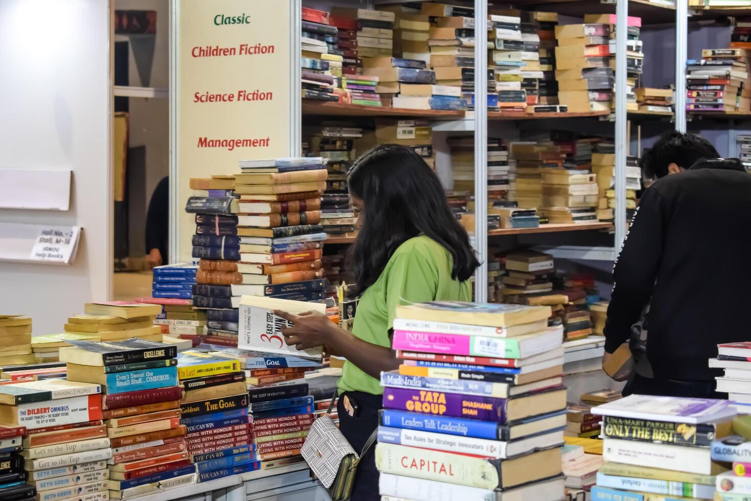 Delhi, India, July 17 2024 - Various age group people reading variety of Books on shelf inside a book-stall at Delhi International Book Fair, Books in Annual Book Fair at Bharat Mandapam complex photo