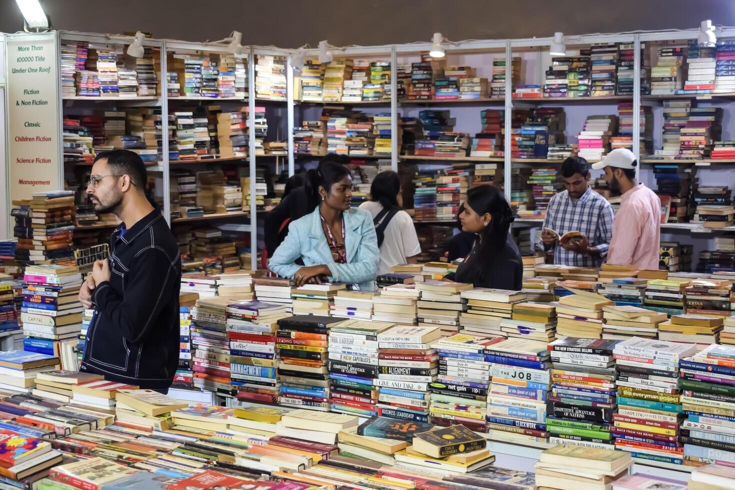 Delhi, India, July 17 2024 - Various age group people reading variety of Books on shelf inside a book-stall at Delhi International Book Fair, Books in Annual Book Fair at Bharat Mandapam complex photo