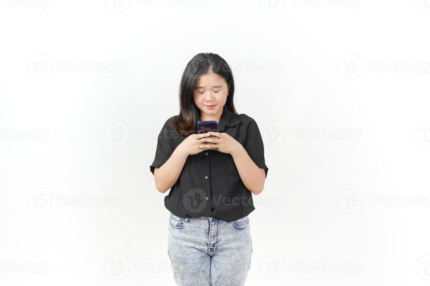 Young Asian woman Holding and Using Smartphone, Texting or Chatting concept wearing Black t-shirt and jeans isolated on white background photo