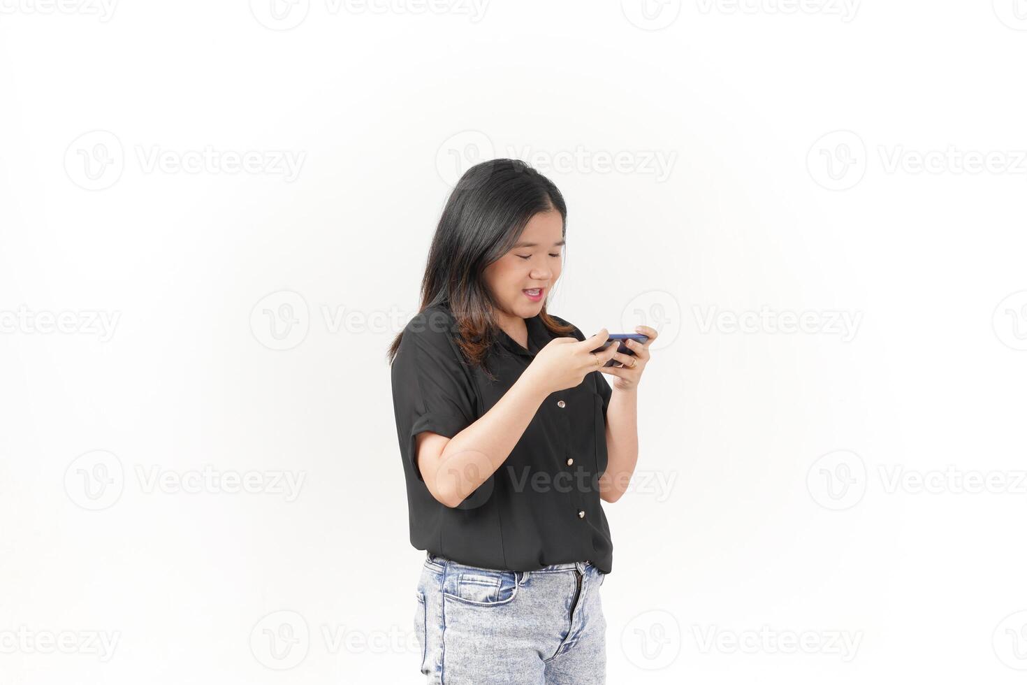 Young Asian woman playing game on smartphone wearing Black t-shirt and jeans isolated on white background photo