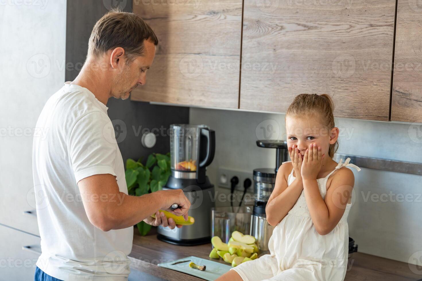 Family with a young father and his little daughter preparing a healthy juice or smoothie with fresh fruits in home kitchen. High quality photo