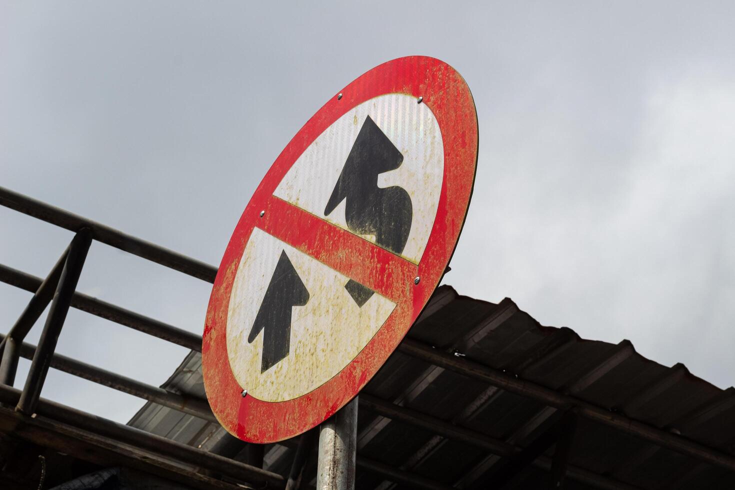 The winding road sign is made of metal and is red and white in color. photo