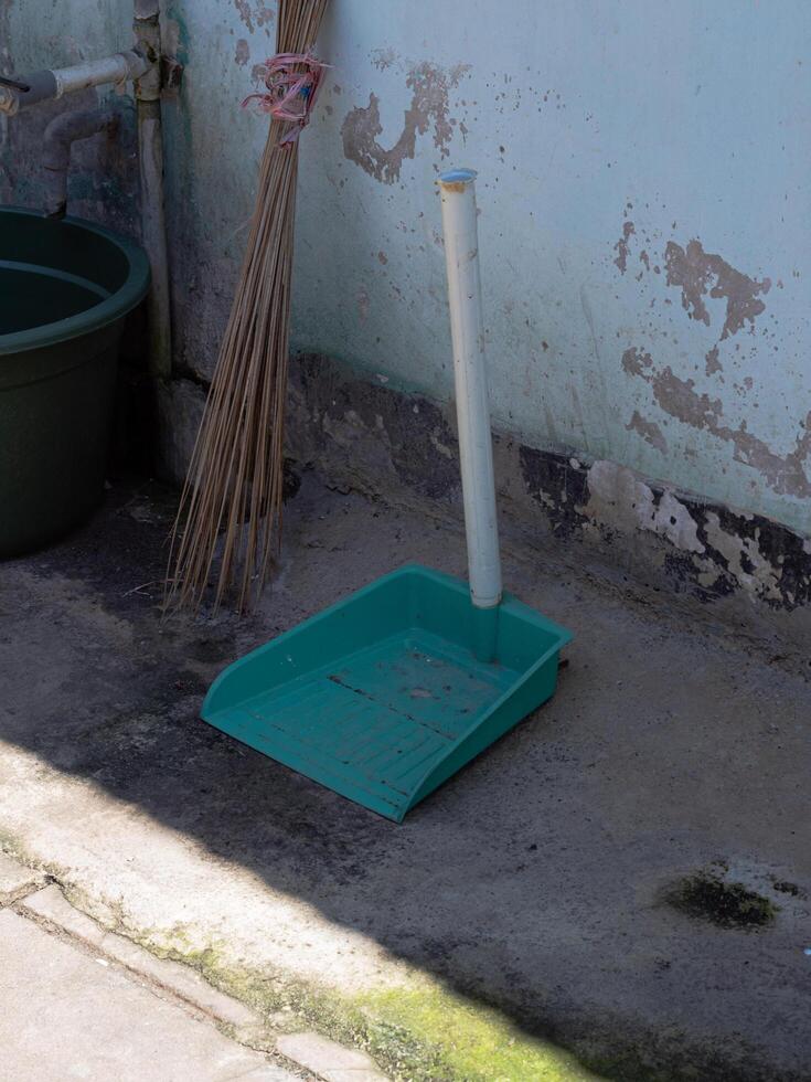 Green cleaning tool with broom beside it photo