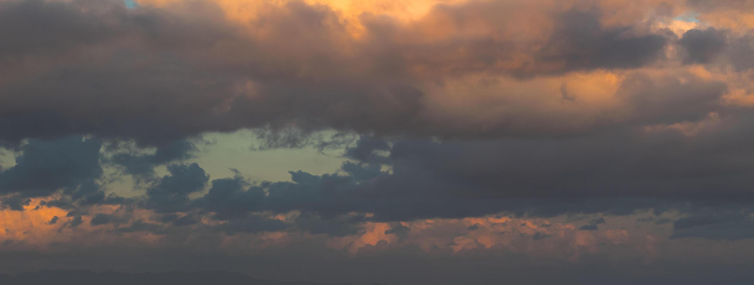 Dramatic clouds in the blue sky in the morning, the rising sun rays hitting the clouds photo