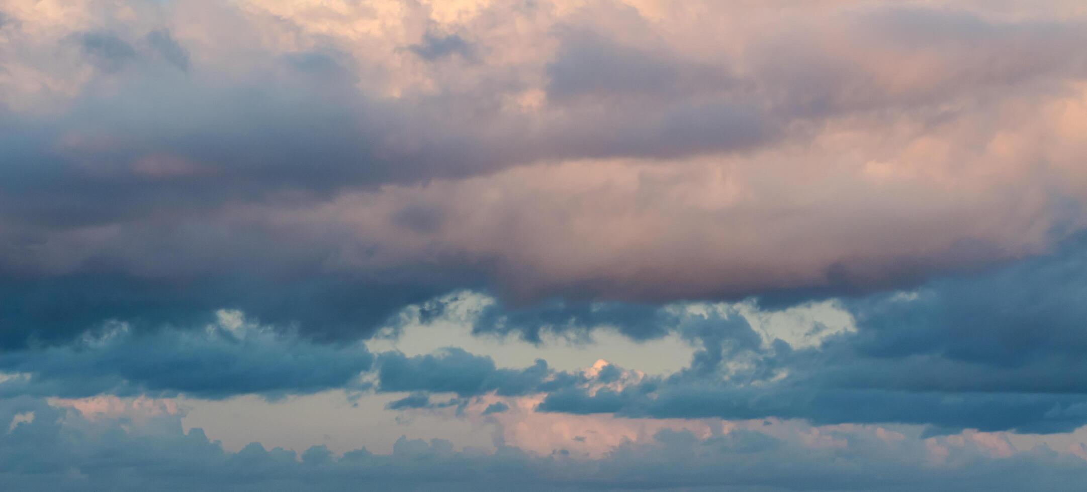 Dramatic clouds in the blue sky in the morning, the rising sun rays hitting the clouds photo