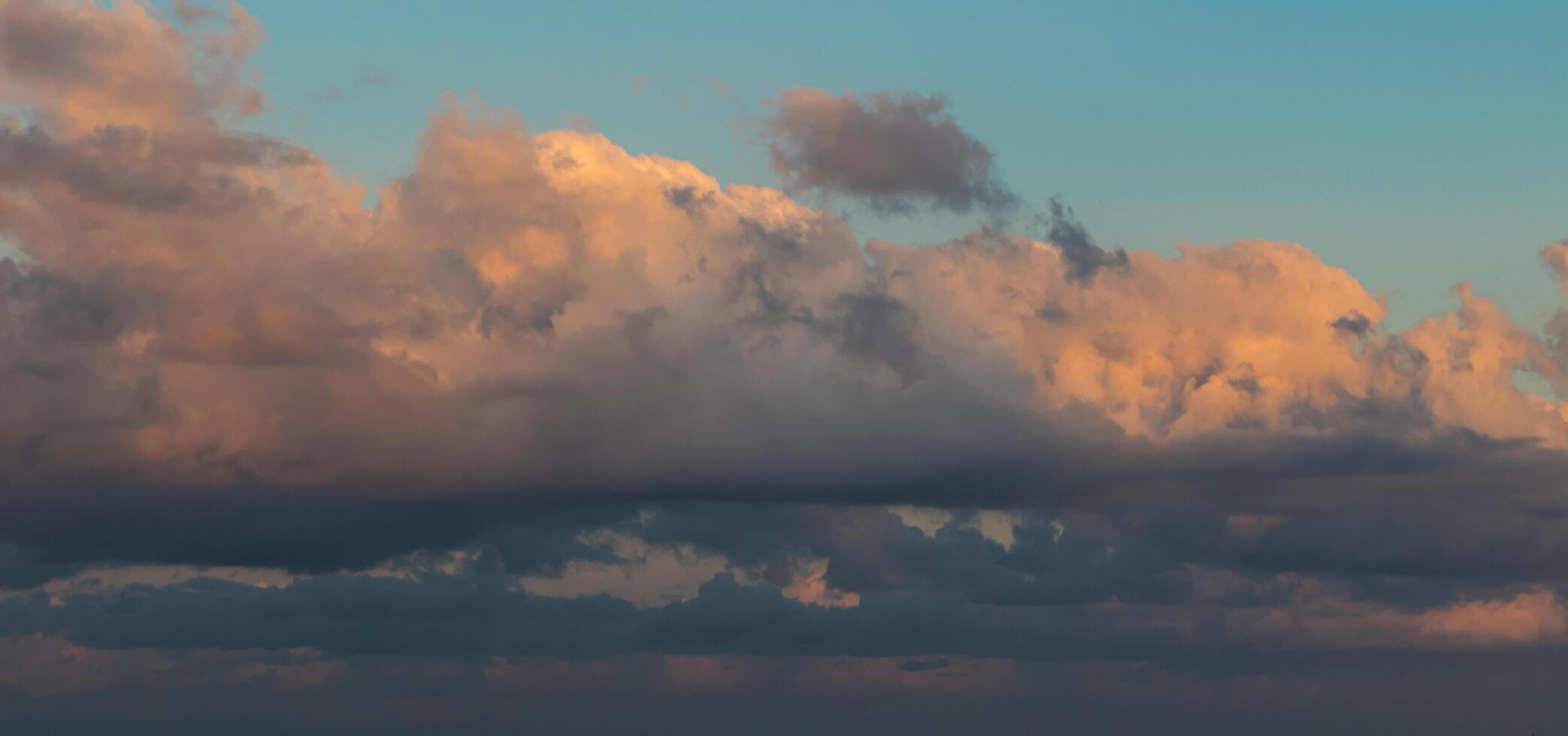 Dramatic clouds in the blue sky in the morning, the rising sun rays hitting the clouds photo