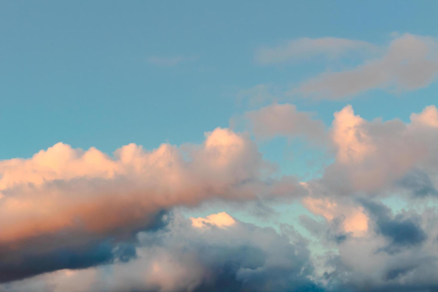 Dramatic clouds in the blue sky in the morning, the rising sun rays hitting the clouds photo