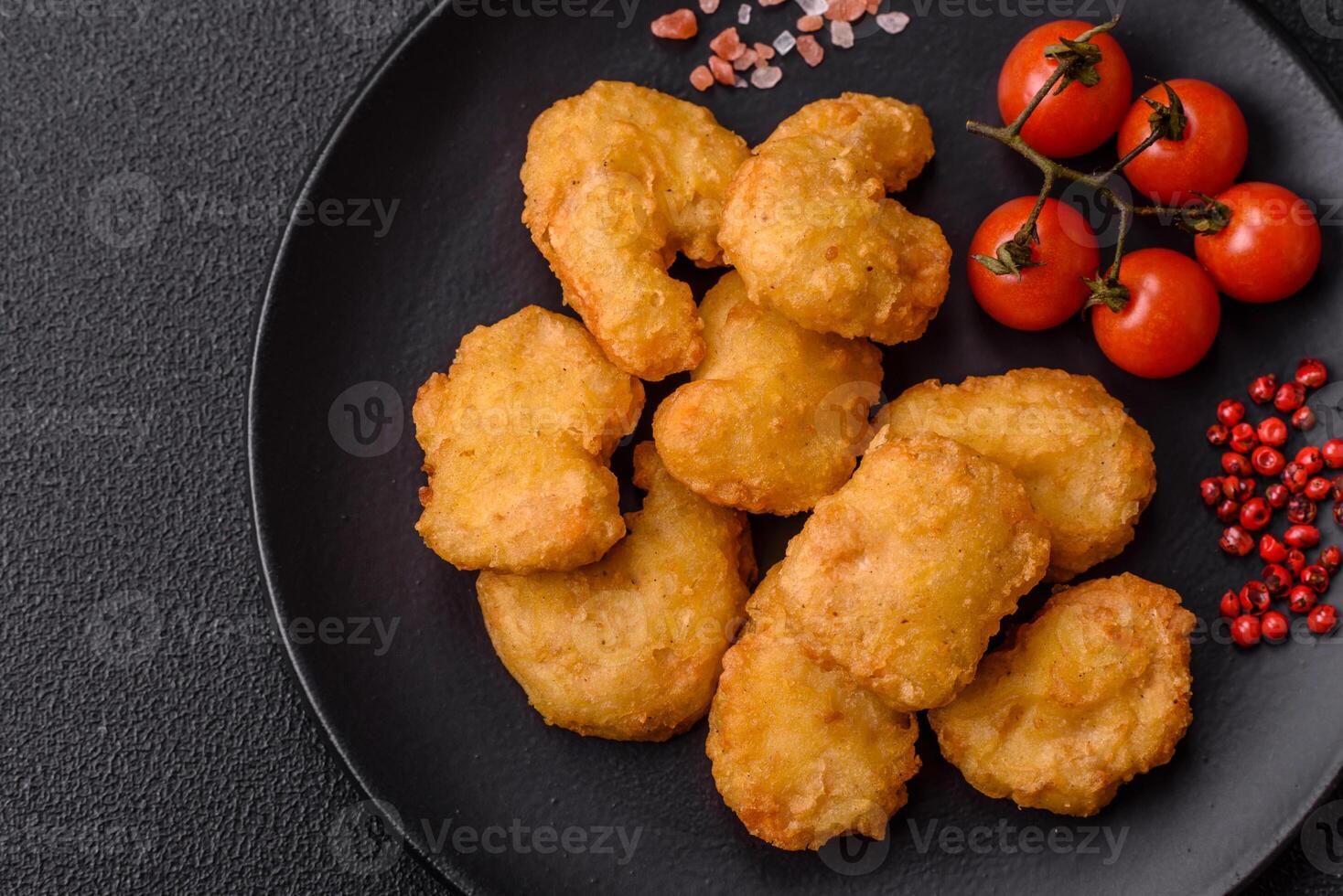 Delicious fresh crispy chicken nuggets on a dark concrete background photo