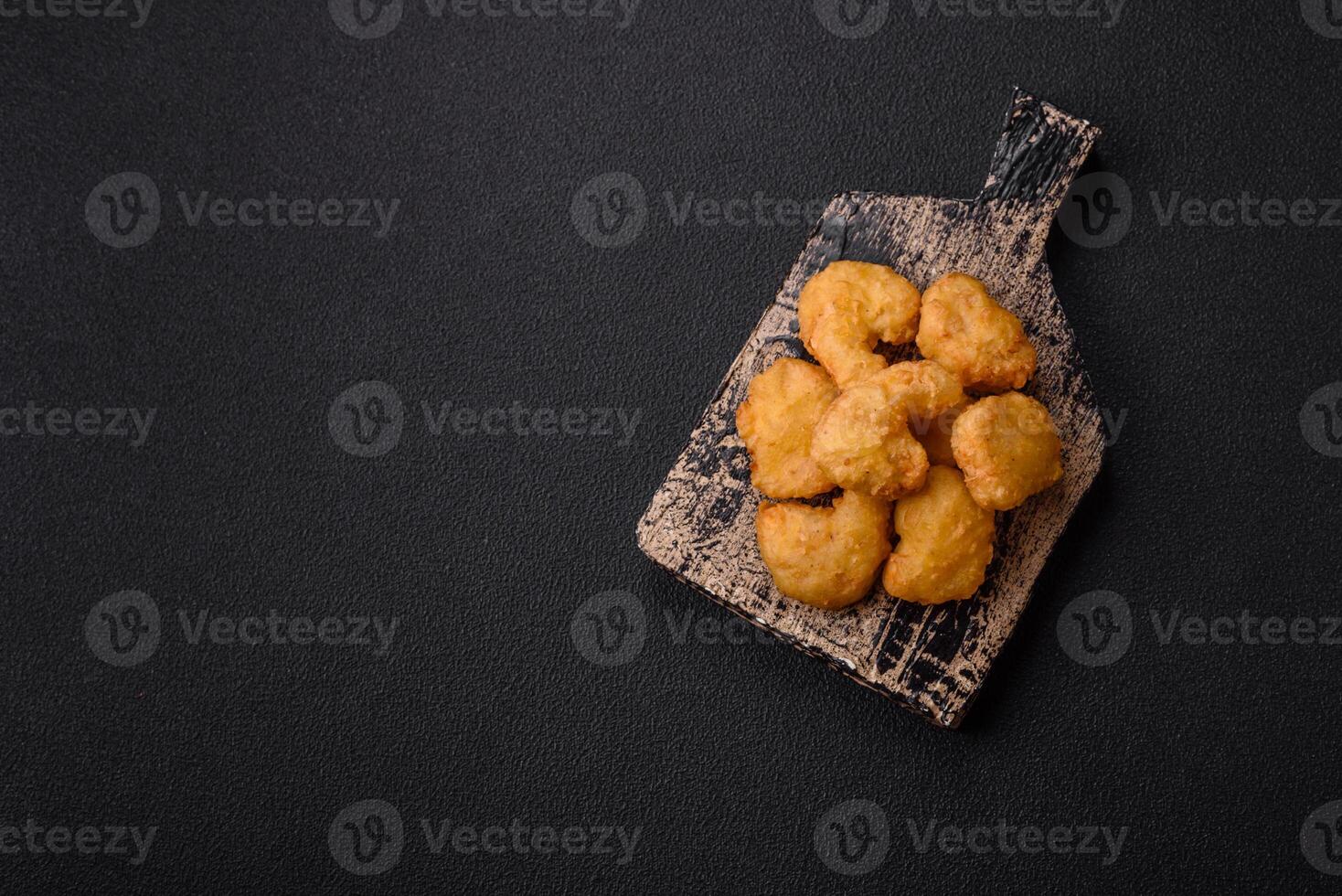 Delicious fresh crispy chicken nuggets on a dark concrete background photo