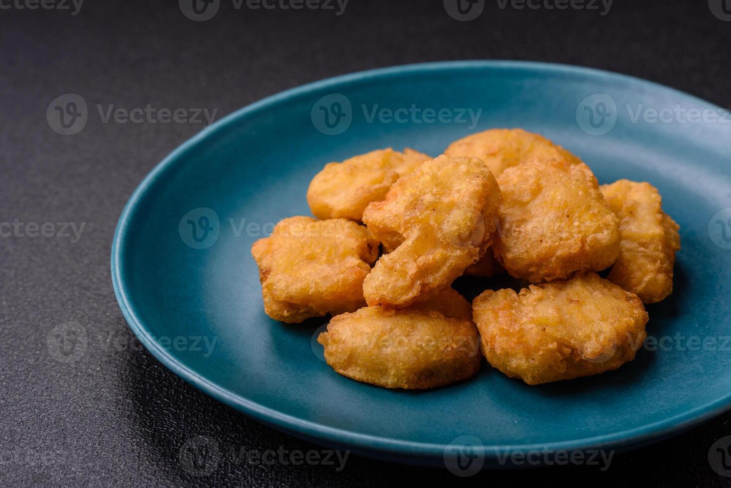 Delicious fresh crispy chicken nuggets on a dark concrete background photo
