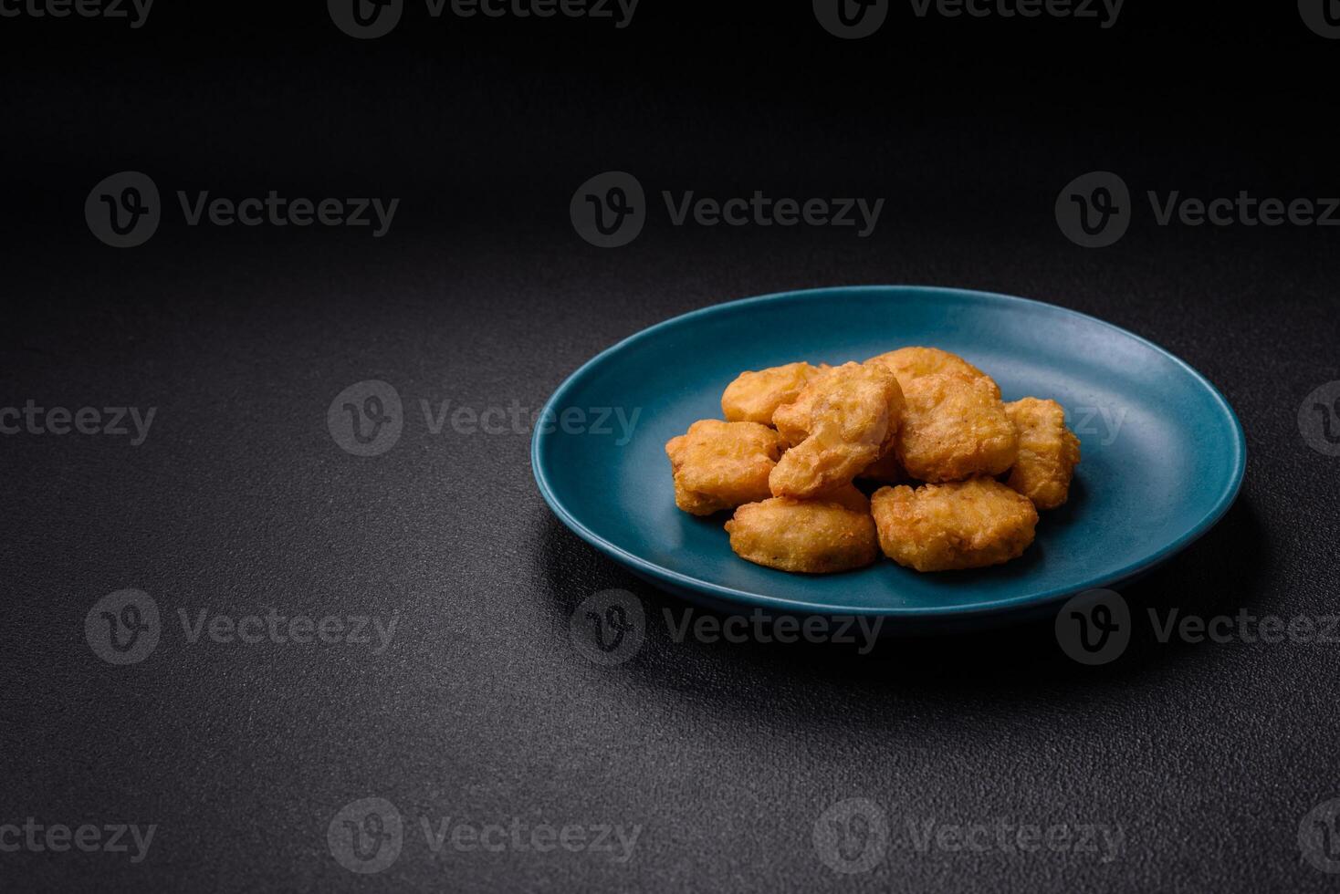 Delicious fresh crispy chicken nuggets on a dark concrete background photo