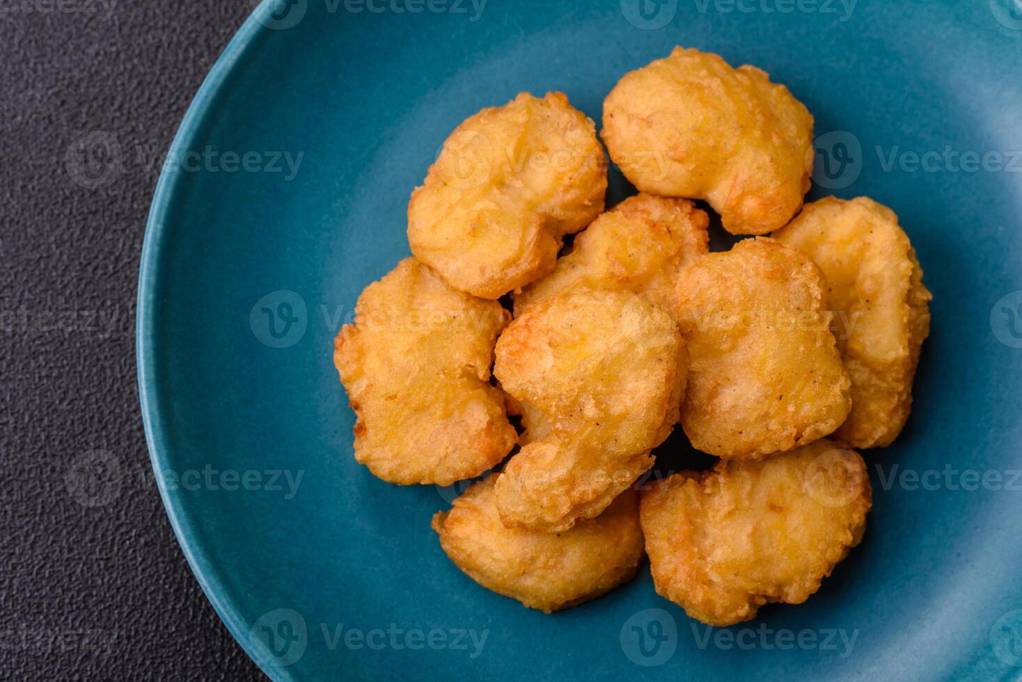 Delicious fresh crispy chicken nuggets on a dark concrete background photo