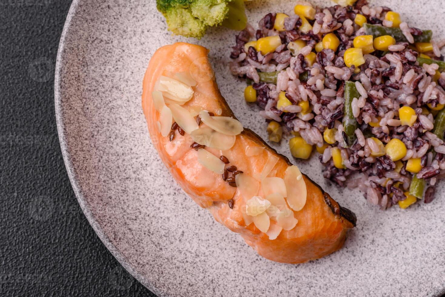 A piece of boiled salmon with rice, broccoli, salt and spices photo