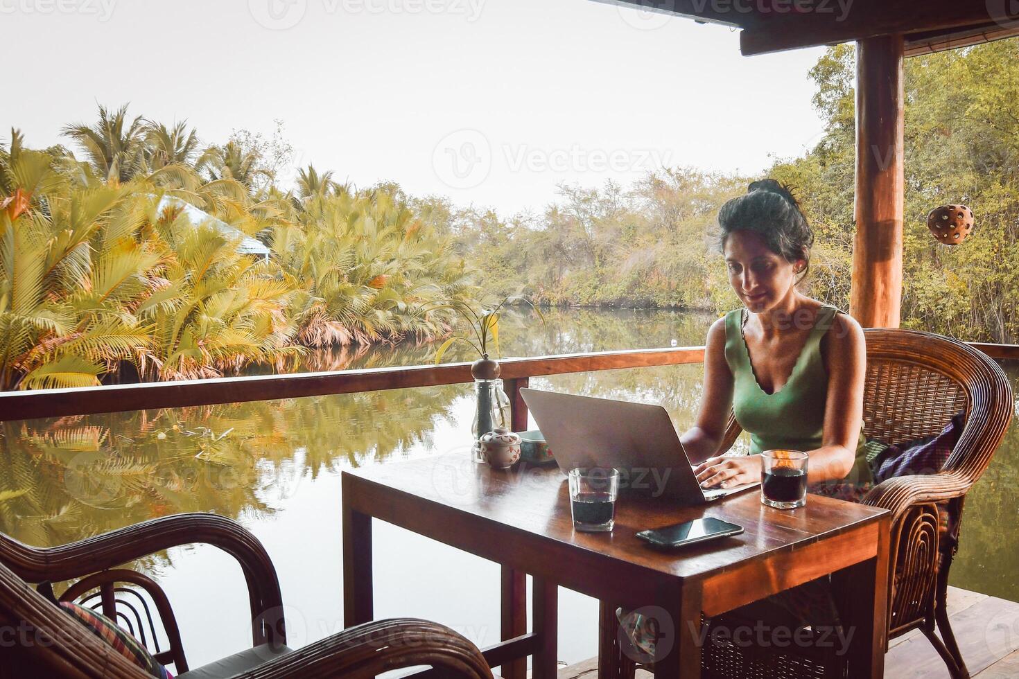 Close up young caucasian woman sit by table in cafe use laptop on holidays in southeast asia in beautiful tropical nature. Remote worker work online abroad concept photo