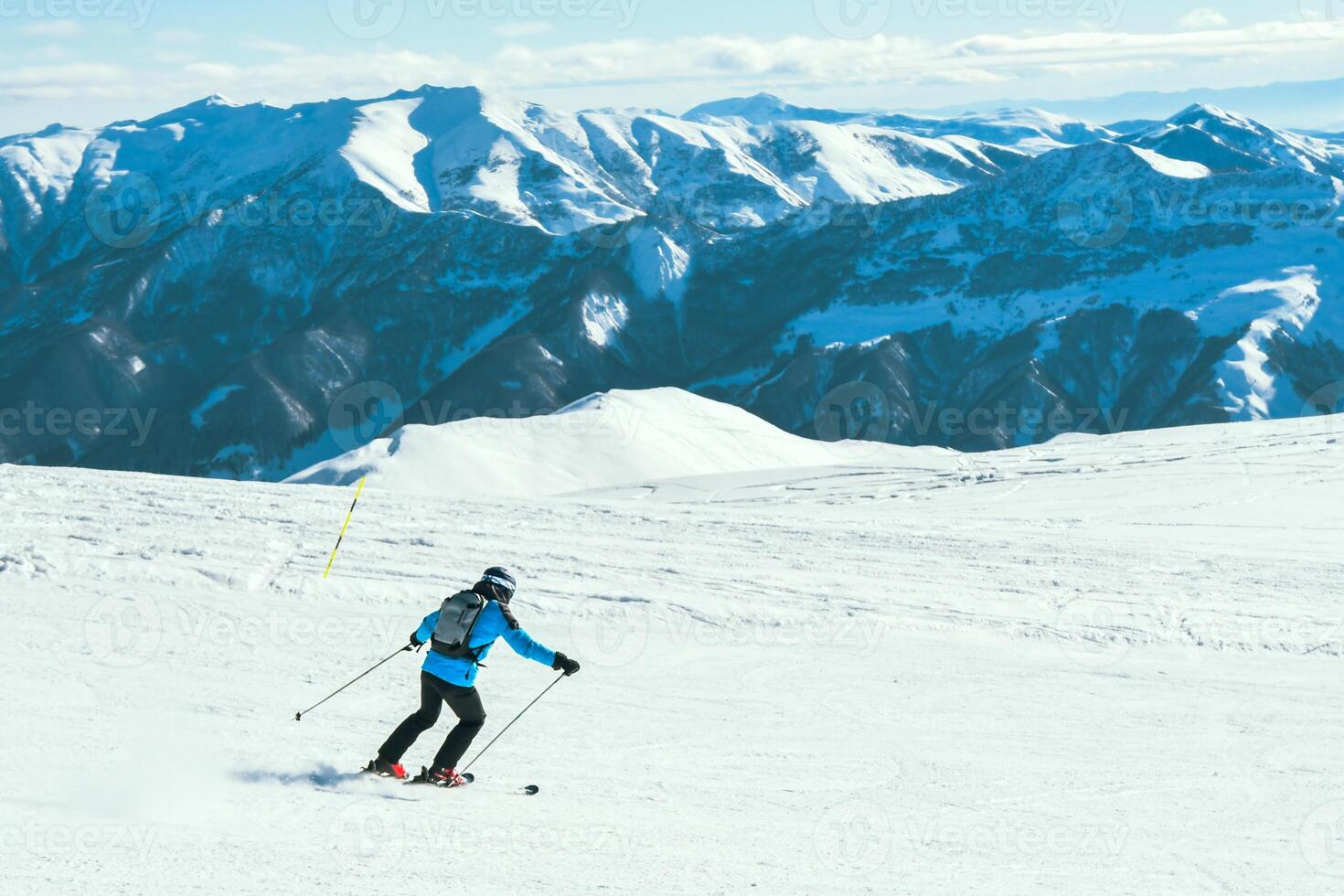 Close up dynamic sports banner of man skier on piste ski downhill fast motion in Alps. Active winter holidays, skiing downhill in overcast day. Ski rides on the track with swirls of fresh snow photo