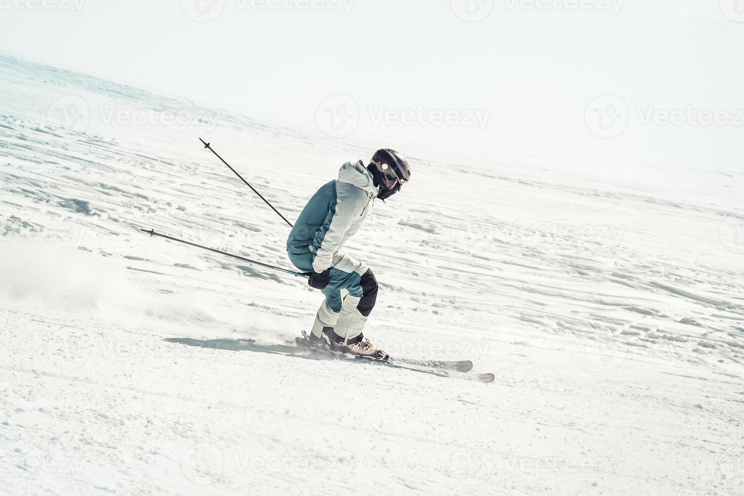 Close up dynamic sports banner of man skier on piste ski downhill fast motion in Alps. Active winter holidays, skiing downhill in overcast day. Ski rides on the track with swirls of fresh snow photo