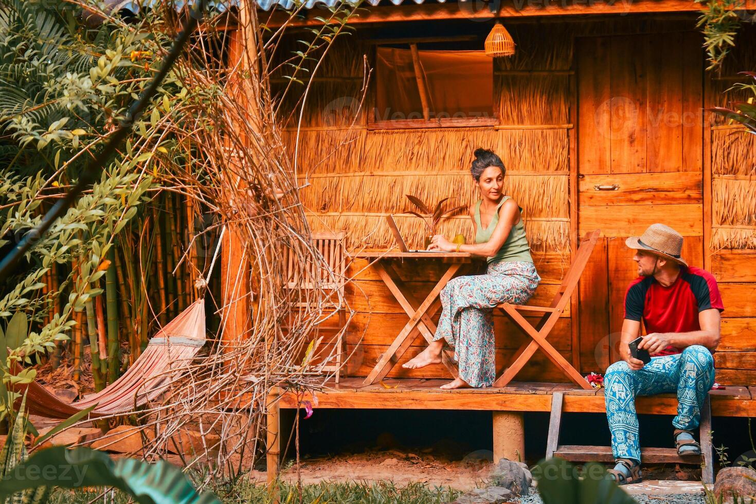 Close up young caucasian hipster couple sit use computer freelance do freelancing work, write travel blog or browse internet search, work online while traveling in southeast asia tropical islands photo