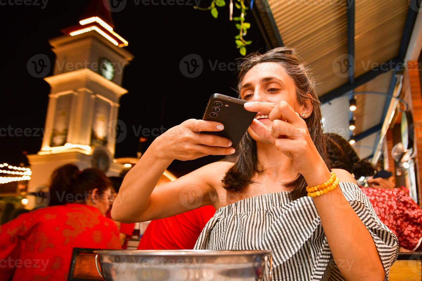 Close up young caucasian woman hold smartphone taking photo of dinner soup meal from top in public busy restaurant. Social media food content creator concept