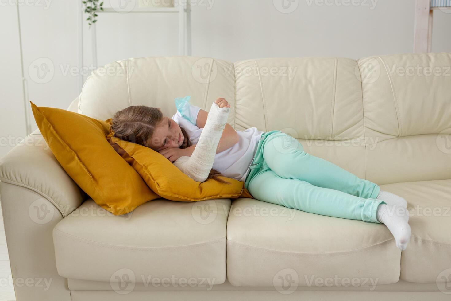 Child with a cast on a broken wrist or arm lying on a couch. Recovery and disease concept. photo