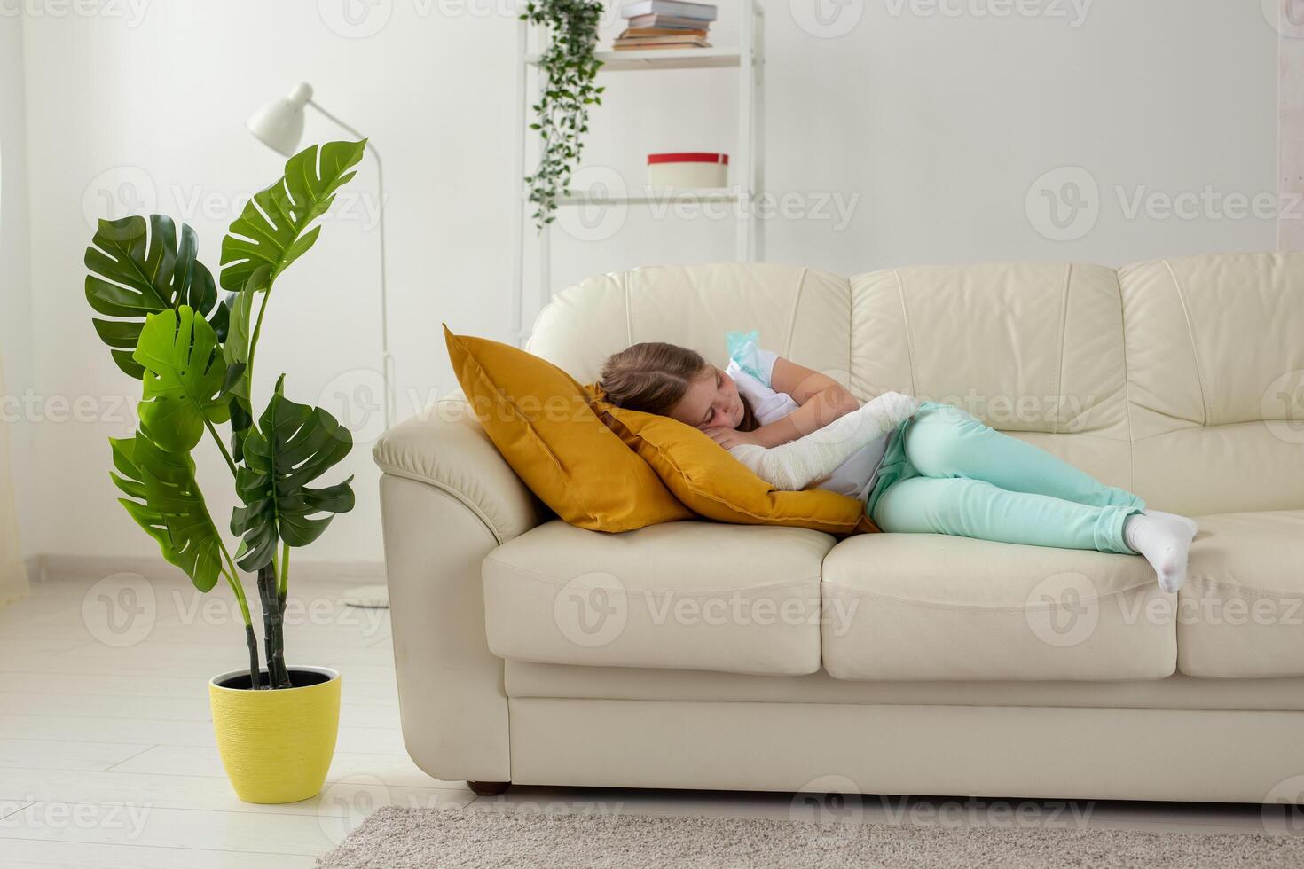 Child with a cast on a broken wrist or arm lying on a couch. Recovery and disease concept. photo