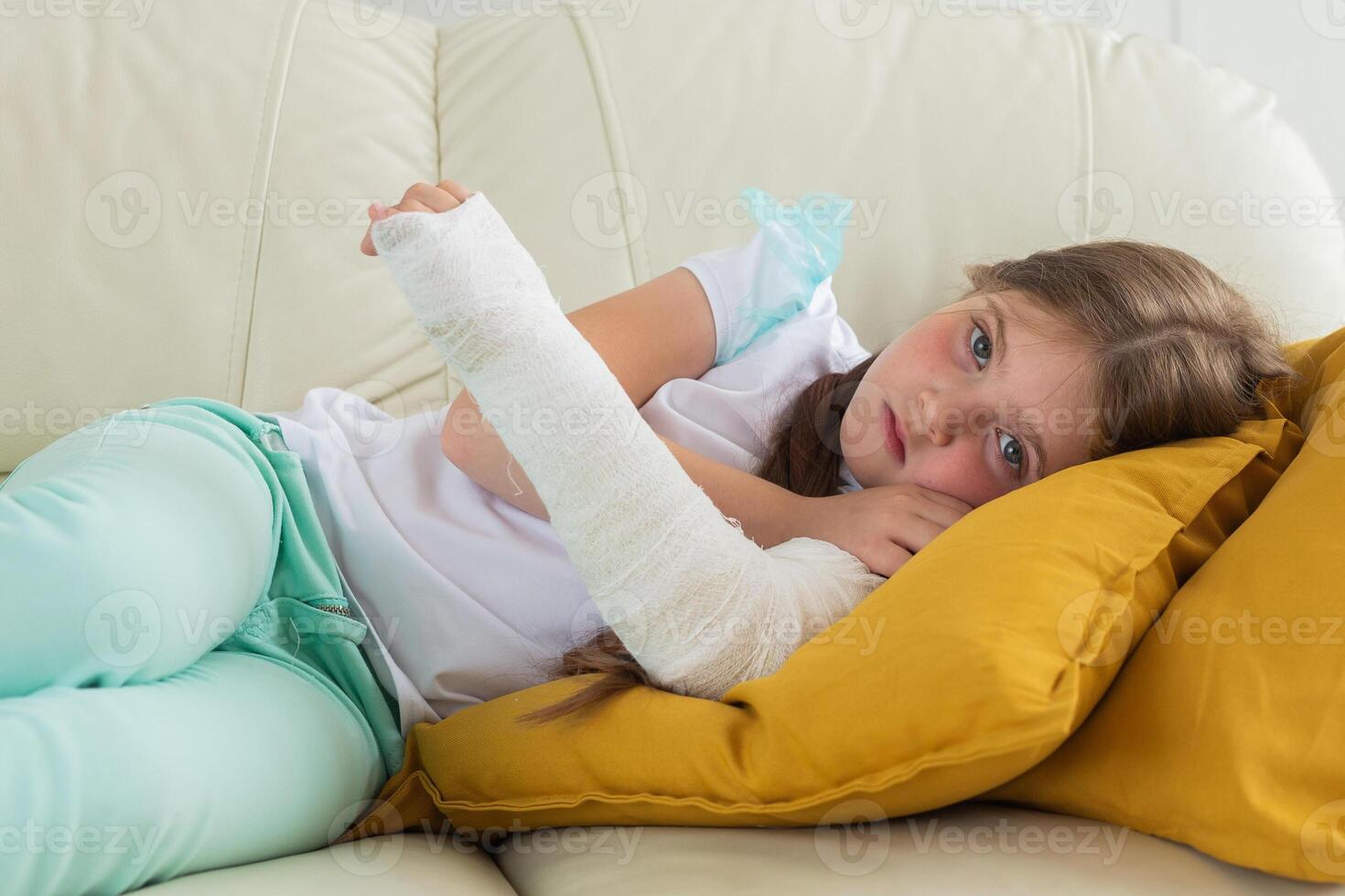 Child with a cast on a broken wrist or arm lying on a couch. Recovery and disease concept. photo