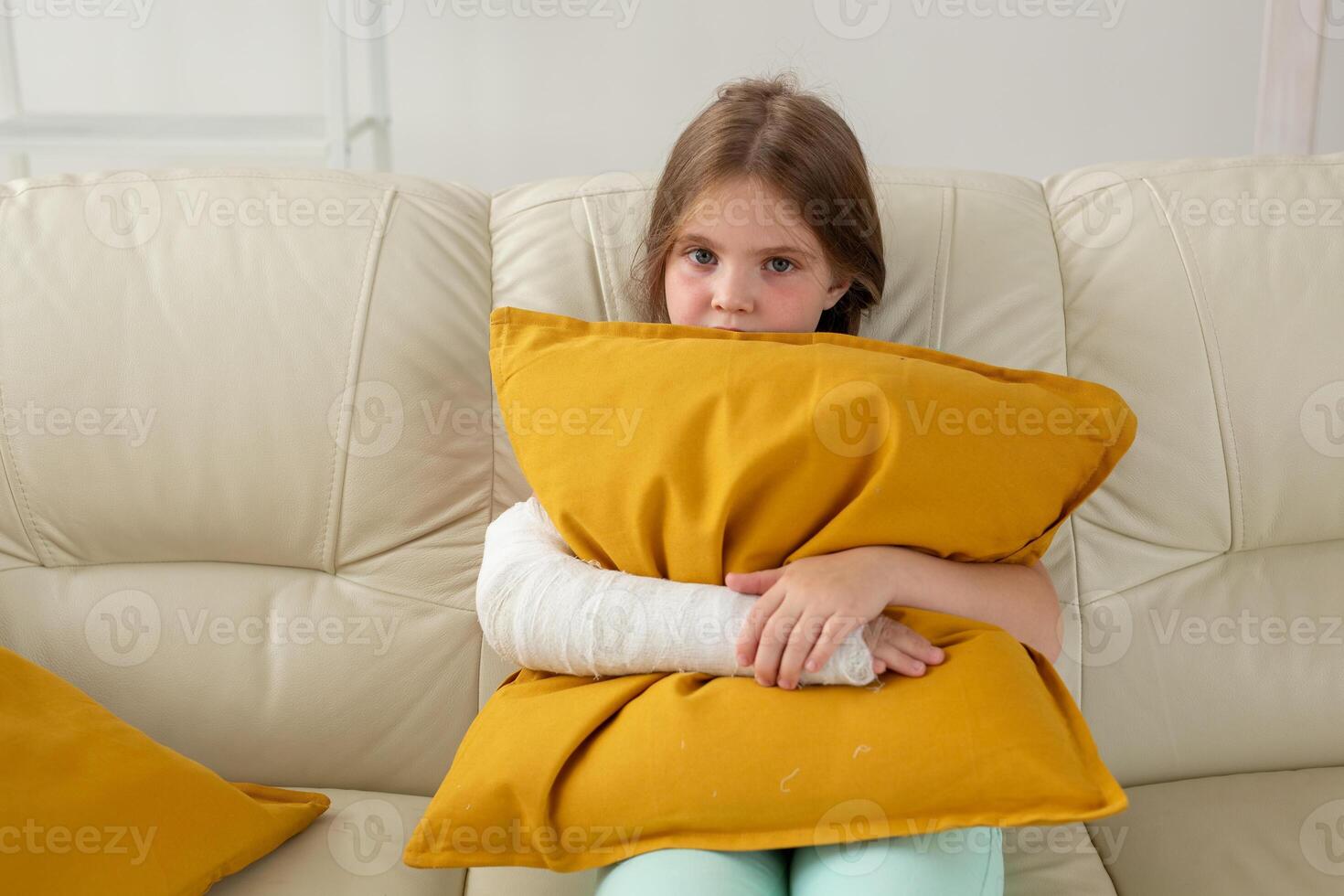 Child with a cast on a broken wrist or arm sitting on a couch. Recovery and disease concept. photo