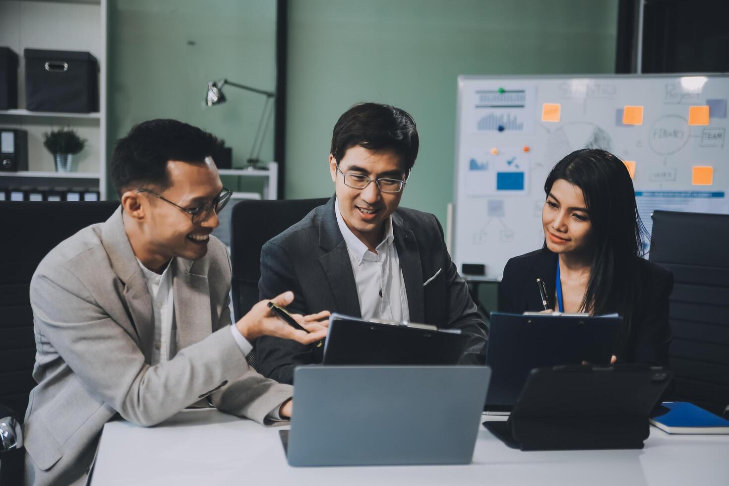 Group of colleagues engaging in a discussion during a business meeting in a conference room. Happy business people, men and women, collaborating and working towards their shared goals. photo