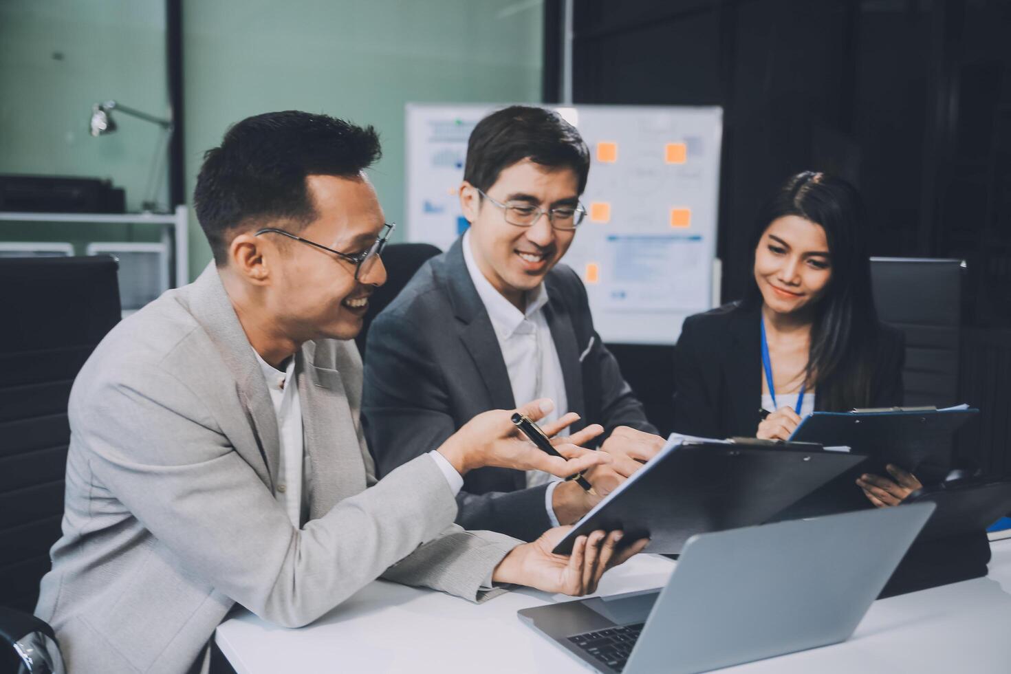 Group of colleagues engaging in a discussion during a business meeting in a conference room. Happy business people, men and women, collaborating and working towards their shared goals. photo
