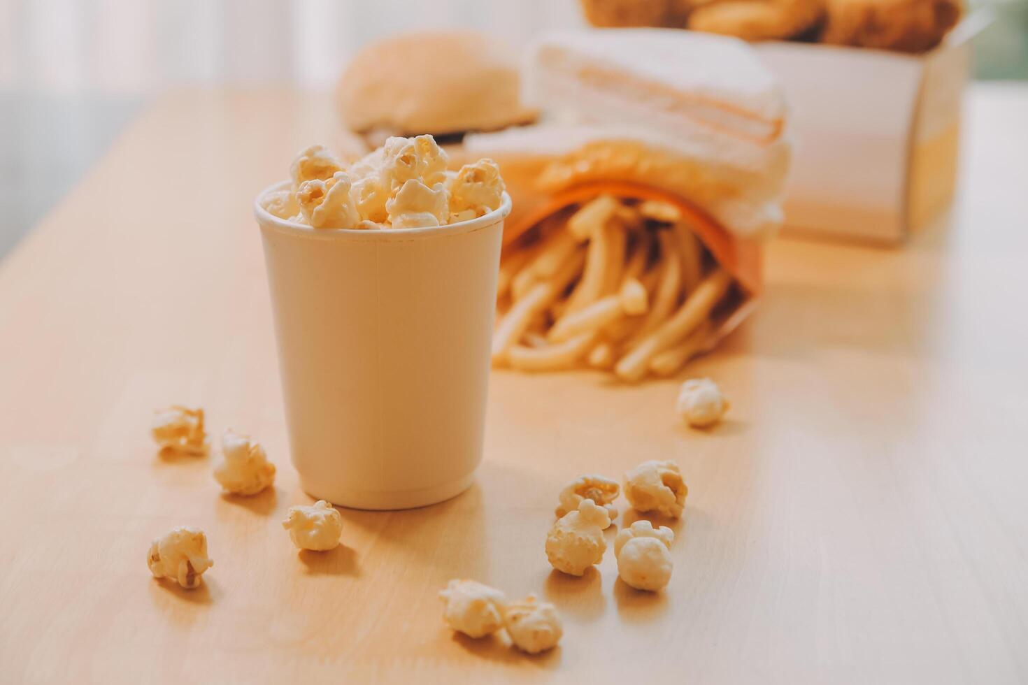 A bucket of popcorn, top-view, warm colors, light brown wooden background, flat lay, daylight macro close-up photo