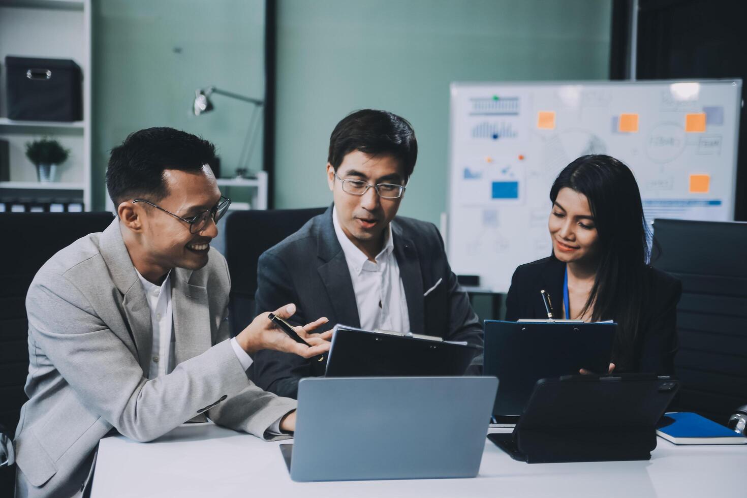Group of colleagues engaging in a discussion during a business meeting in a conference room. Happy business people, men and women, collaborating and working towards their shared goals. photo