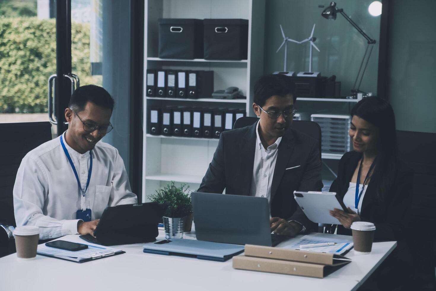 Group of colleagues engaging in a discussion during a business meeting in a conference room. Happy business people, men and women, collaborating and working towards their shared goals. photo