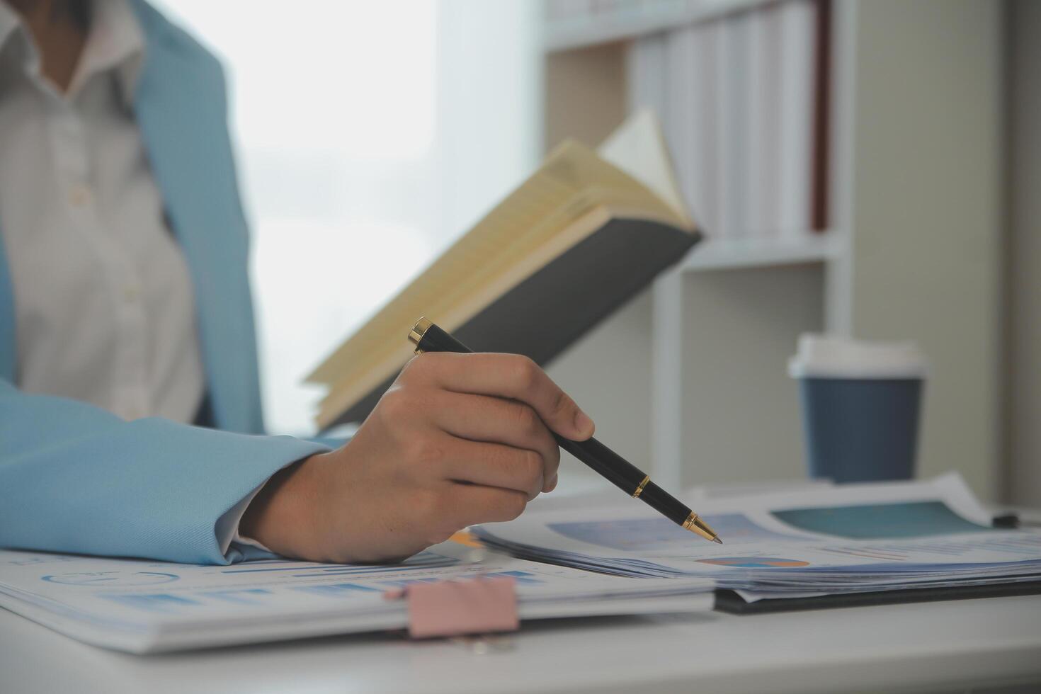 Charming Young asian businesswoman sitting on laptop computer in the office, making report calculating balance Internal Revenue Service checking document. photo