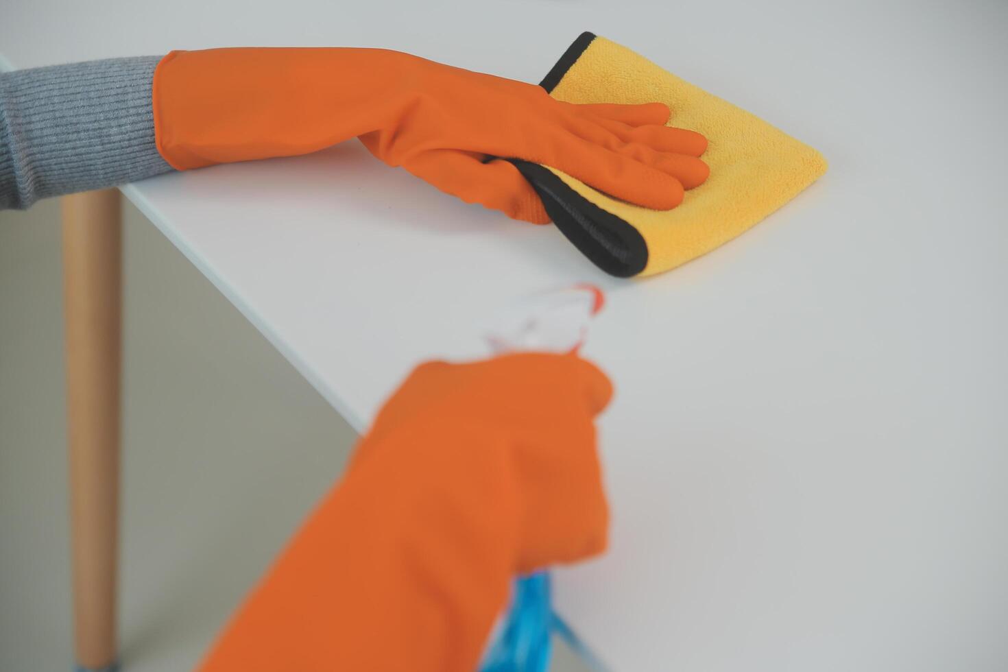 Woman cleaning table using rag and diffuser at home. photo