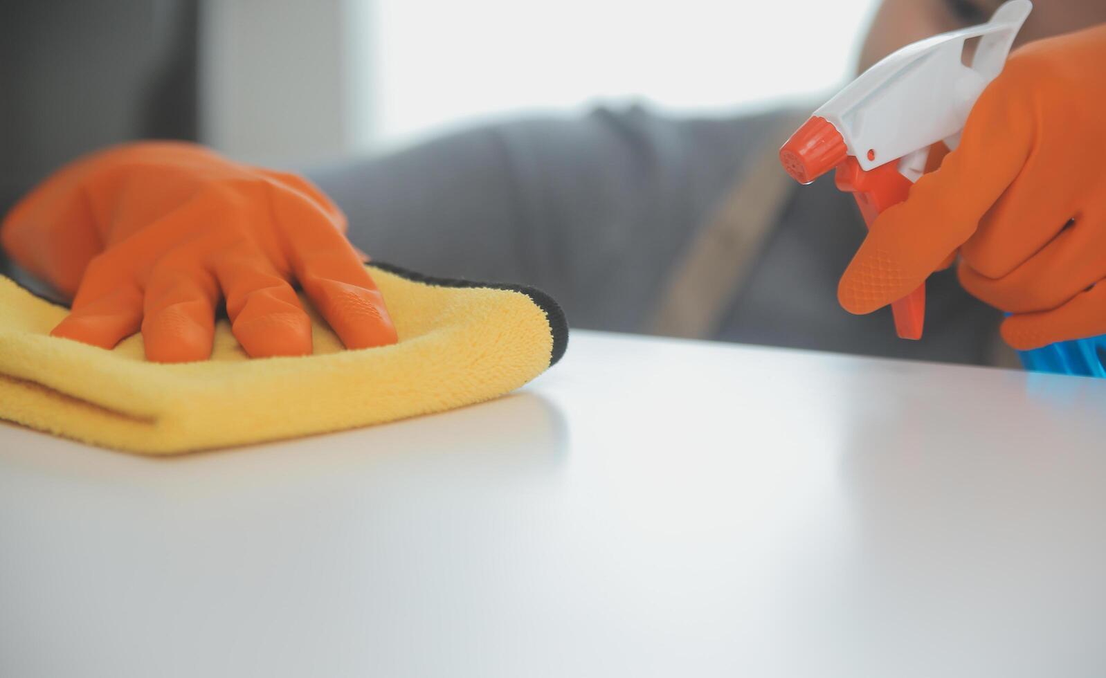 Woman cleaning table using rag and diffuser at home. photo