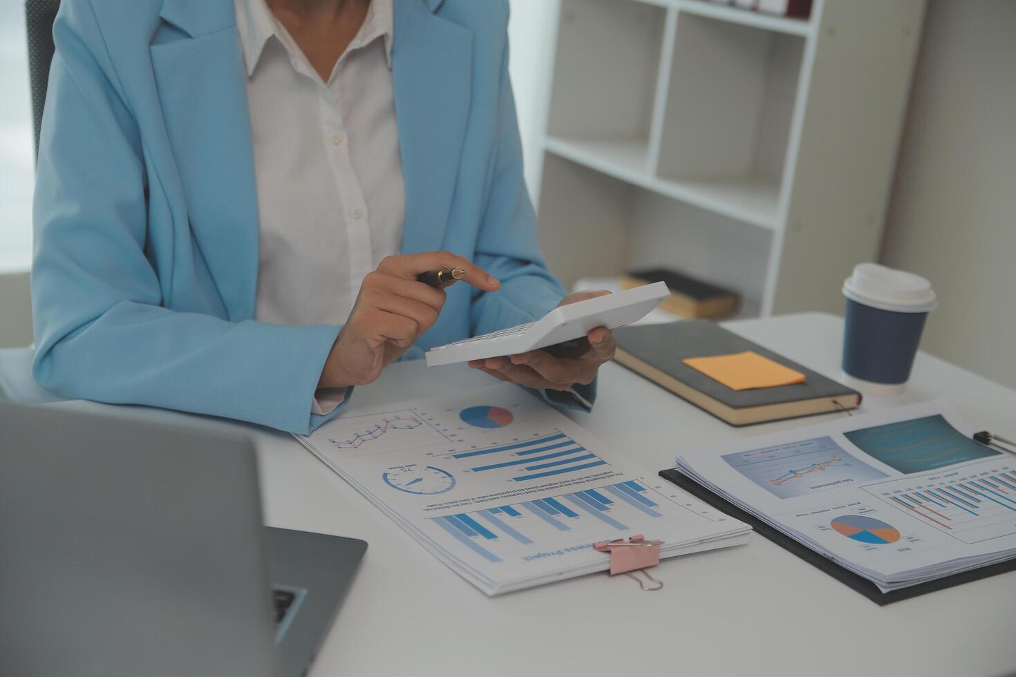 Charming Young asian businesswoman sitting on laptop computer in the office, making report calculating balance Internal Revenue Service checking document. photo