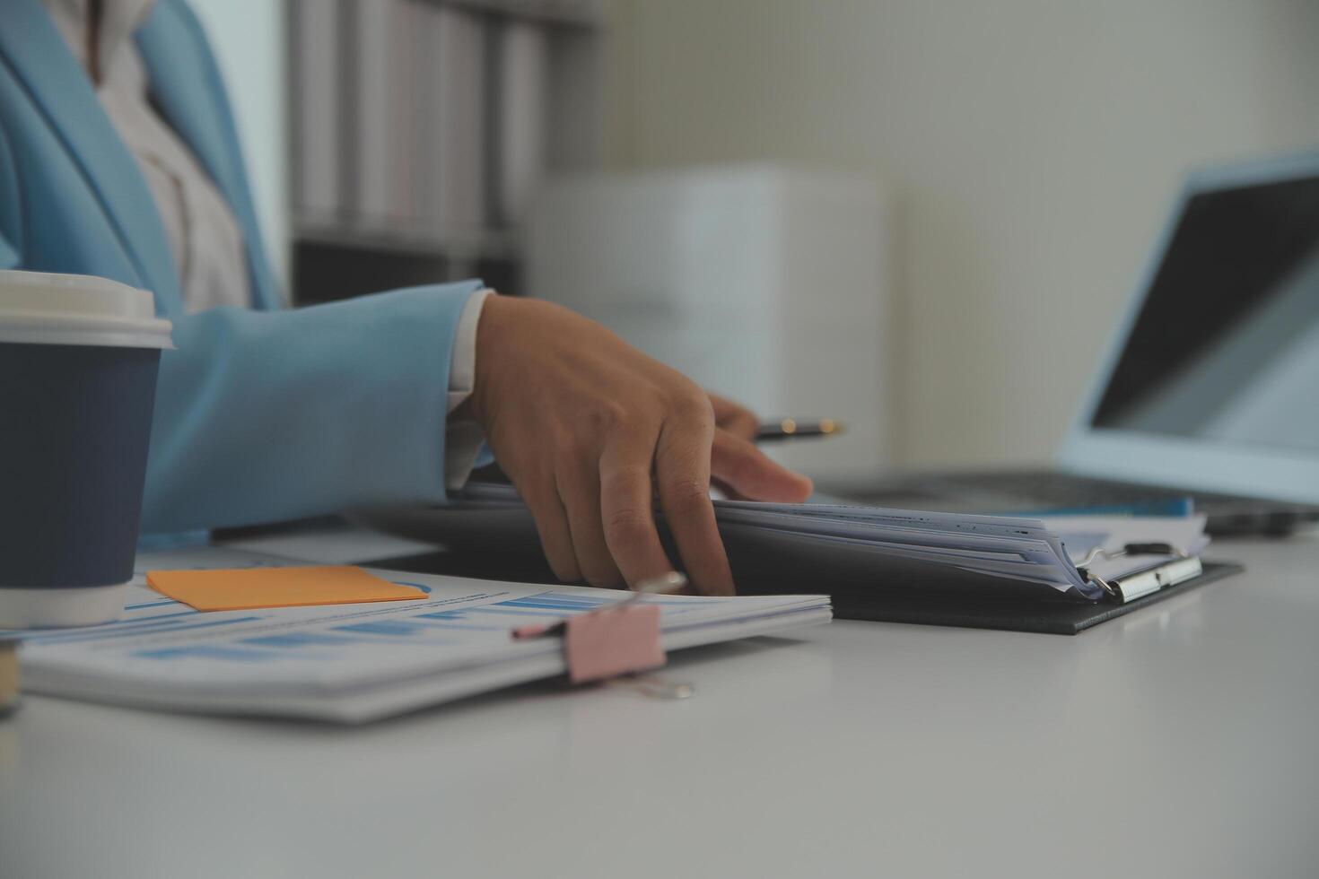 Charming Young asian businesswoman sitting on laptop computer in the office, making report calculating balance Internal Revenue Service checking document. photo