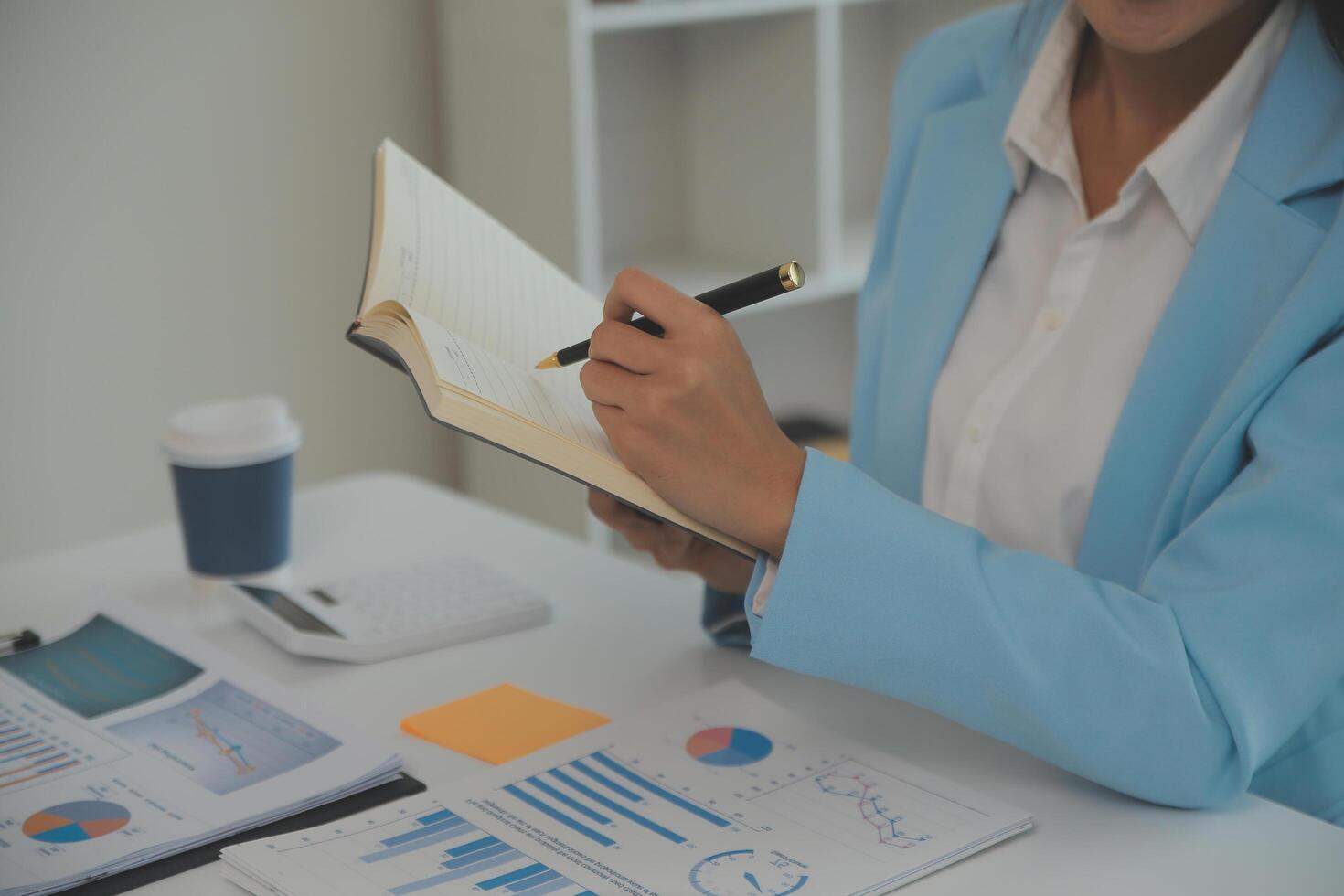 Charming Young asian businesswoman sitting on laptop computer in the office, making report calculating balance Internal Revenue Service checking document. photo
