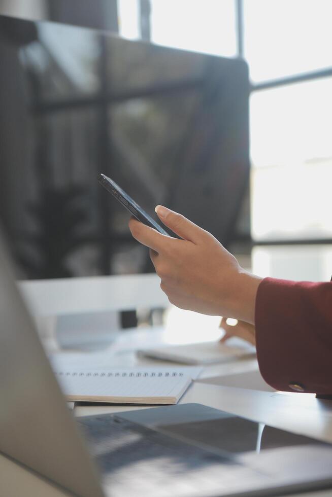 Asian businesswoman in formal suit in office happy and cheerful during using smartphone and working photo