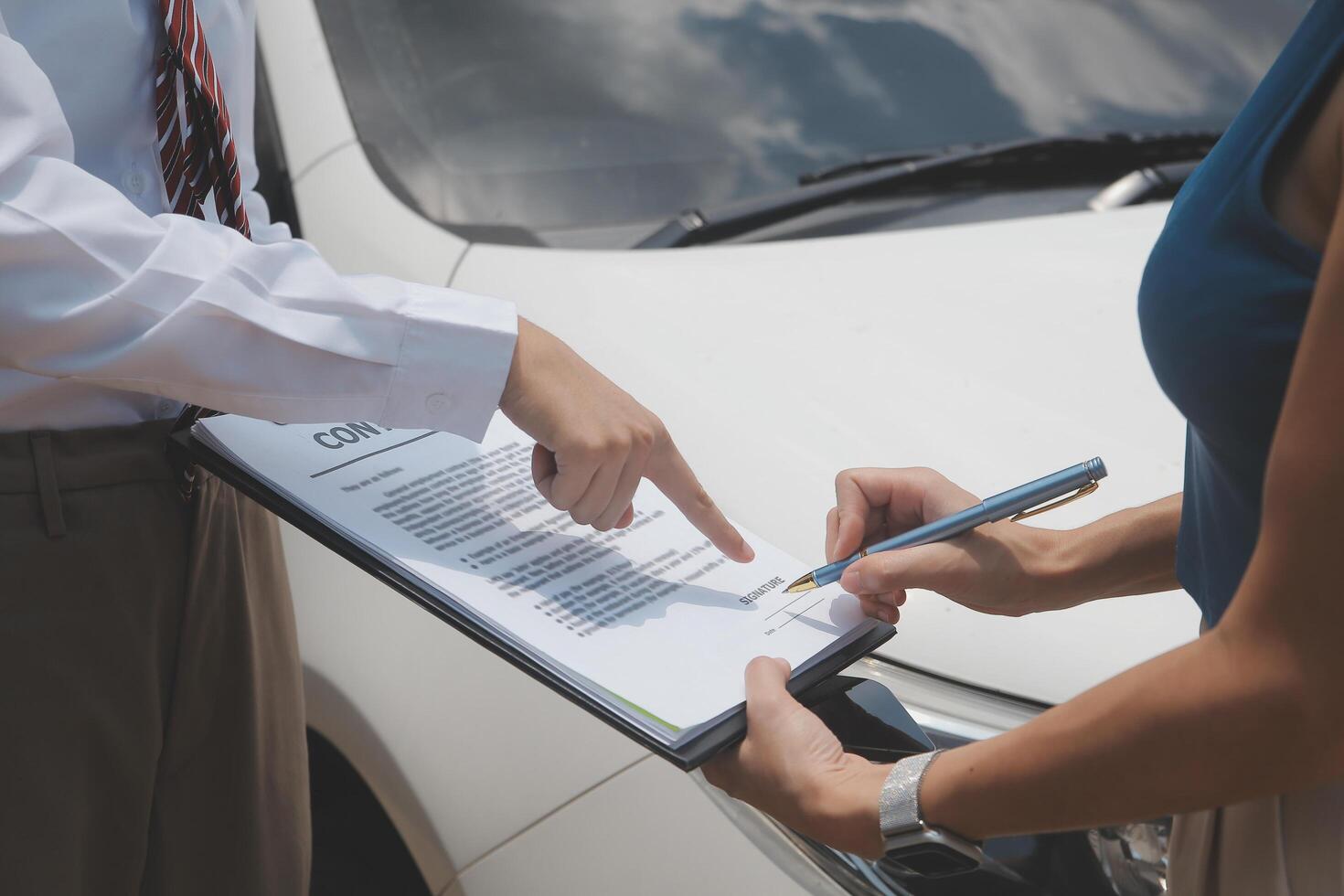 Side view of writing on clipboard while insurance agent examining car after accident photo
