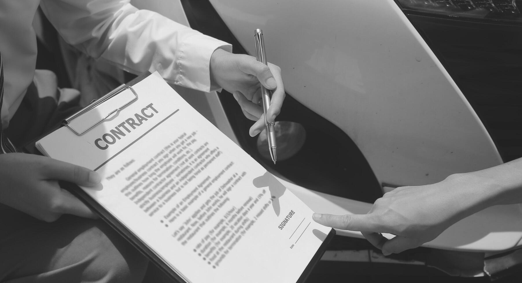 Side view of writing on clipboard while insurance agent examining car after accident photo