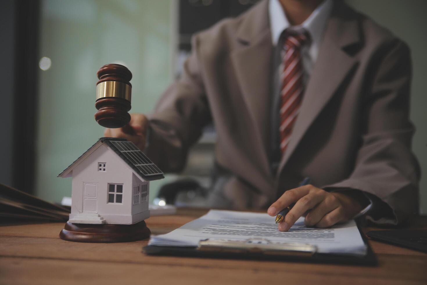 Real Estate Law, Home Insurance, property Tax, Auction and Bidding concepts. small toy house model with gavel justice hammer on desk in courthouse. photo