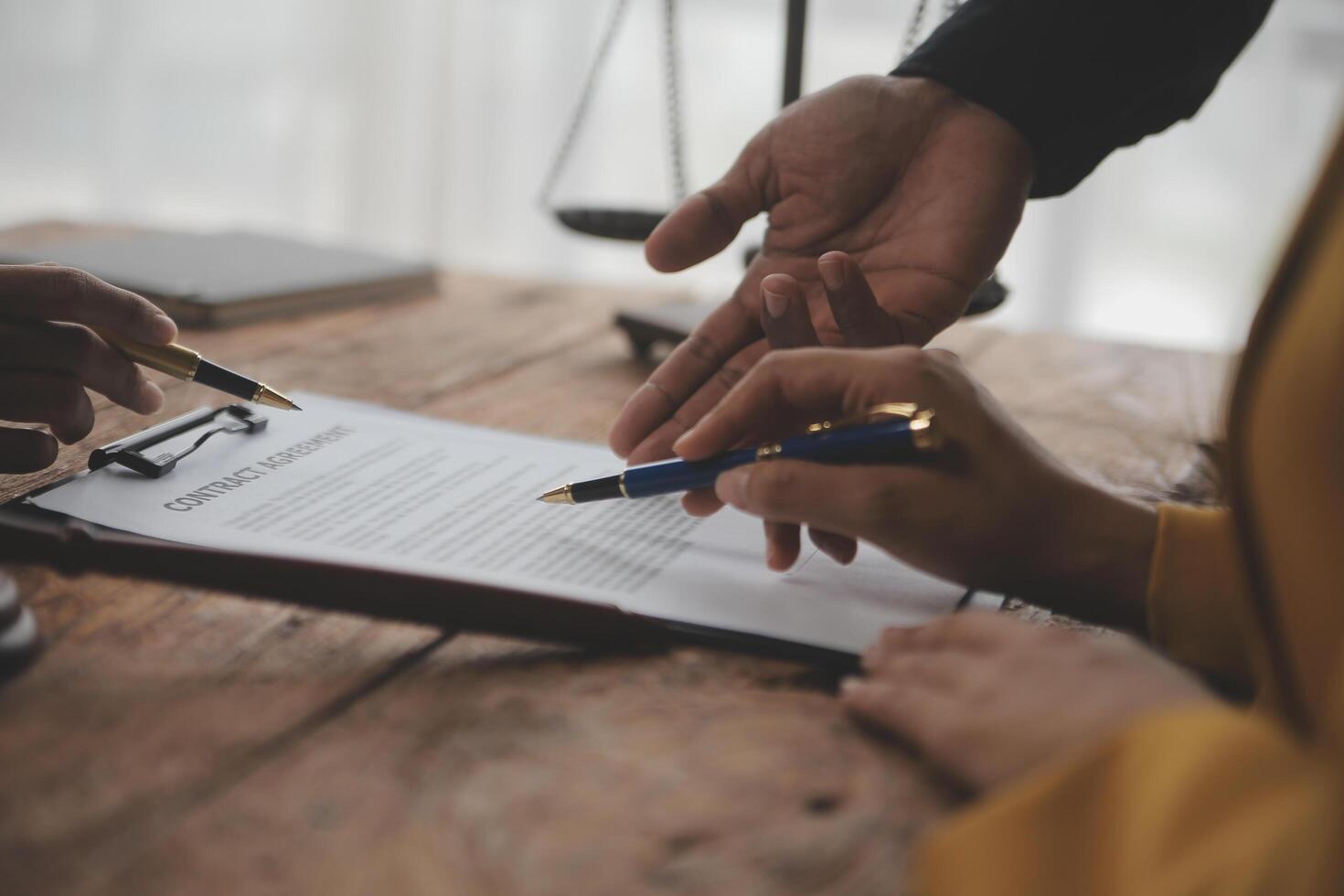 Business and lawyers discussing contract papers with brass scale on desk in office. Law, legal services, advice, justice and law concept picture with film grain effect photo