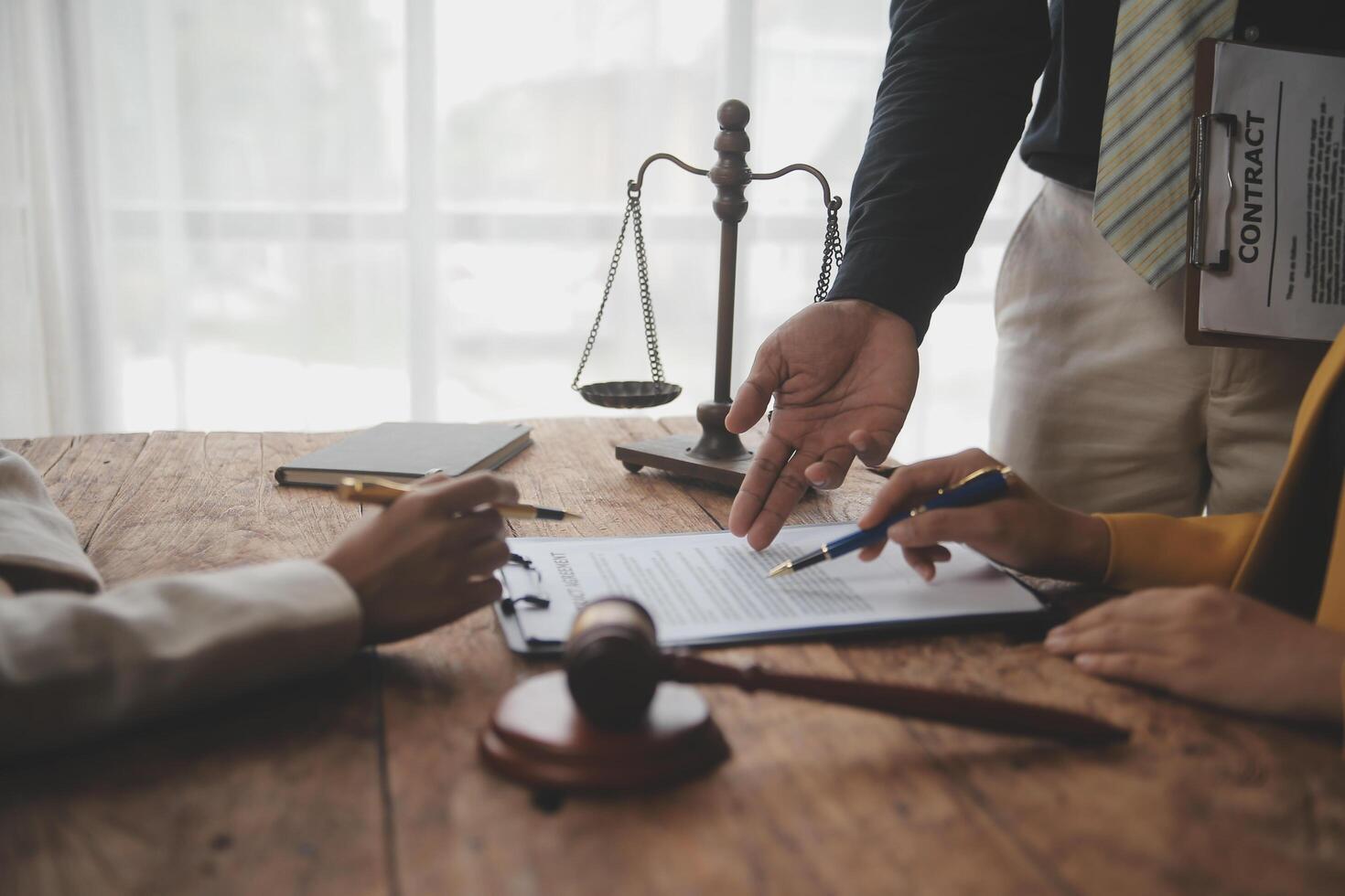 Business and lawyers discussing contract papers with brass scale on desk in office. Law, legal services, advice, justice and law concept picture with film grain effect photo