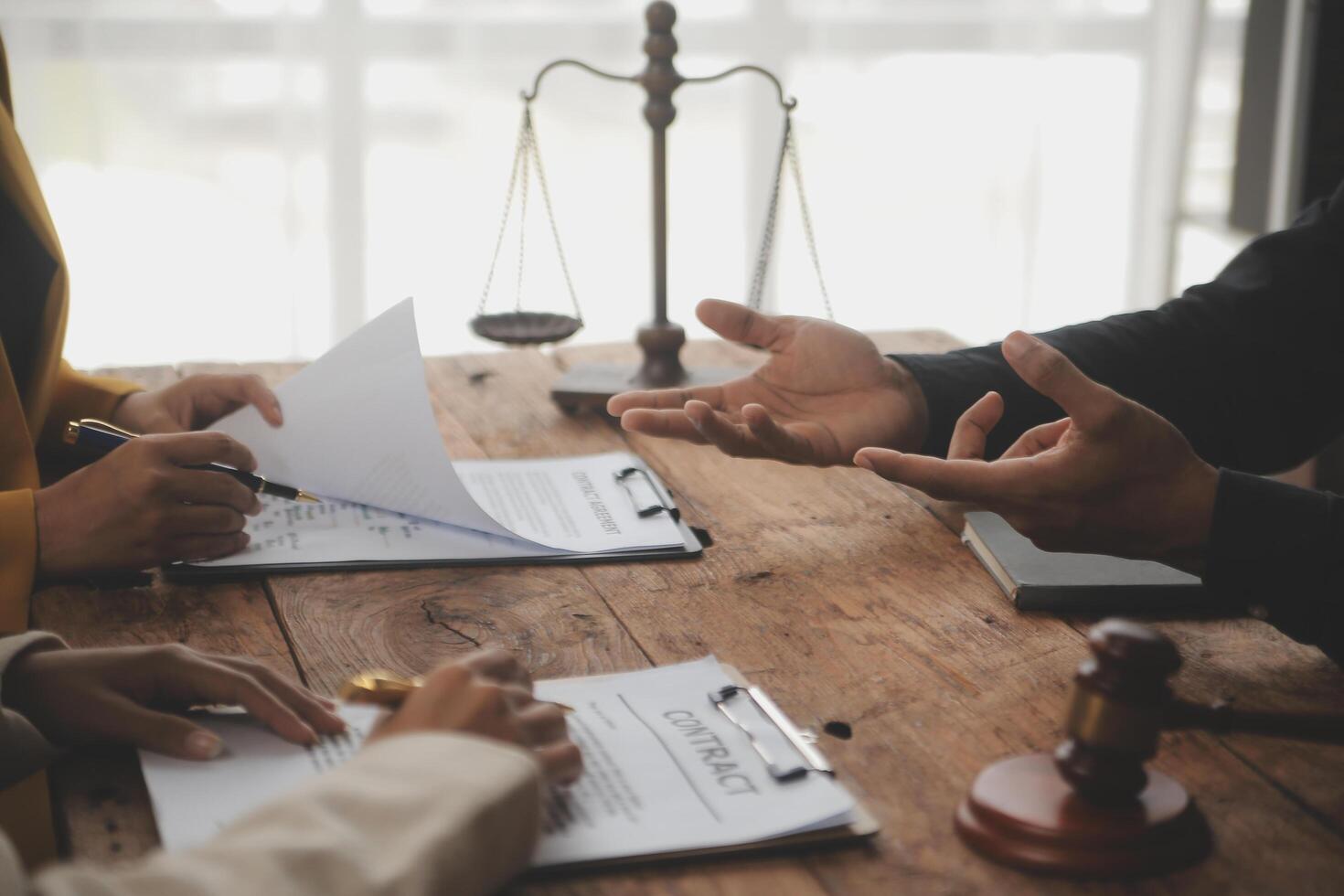 Business and lawyers discussing contract papers with brass scale on desk in office. Law, legal services, advice, justice and law concept picture with film grain effect photo