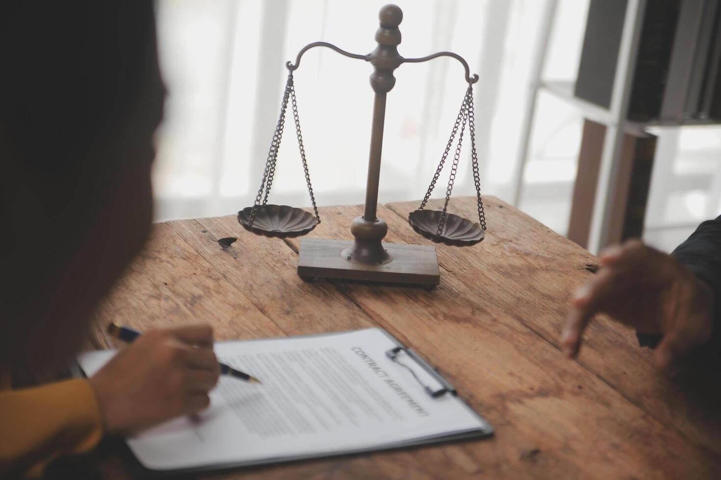 Business and lawyers discussing contract papers with brass scale on desk in office. Law, legal services, advice, justice and law concept picture with film grain effect photo