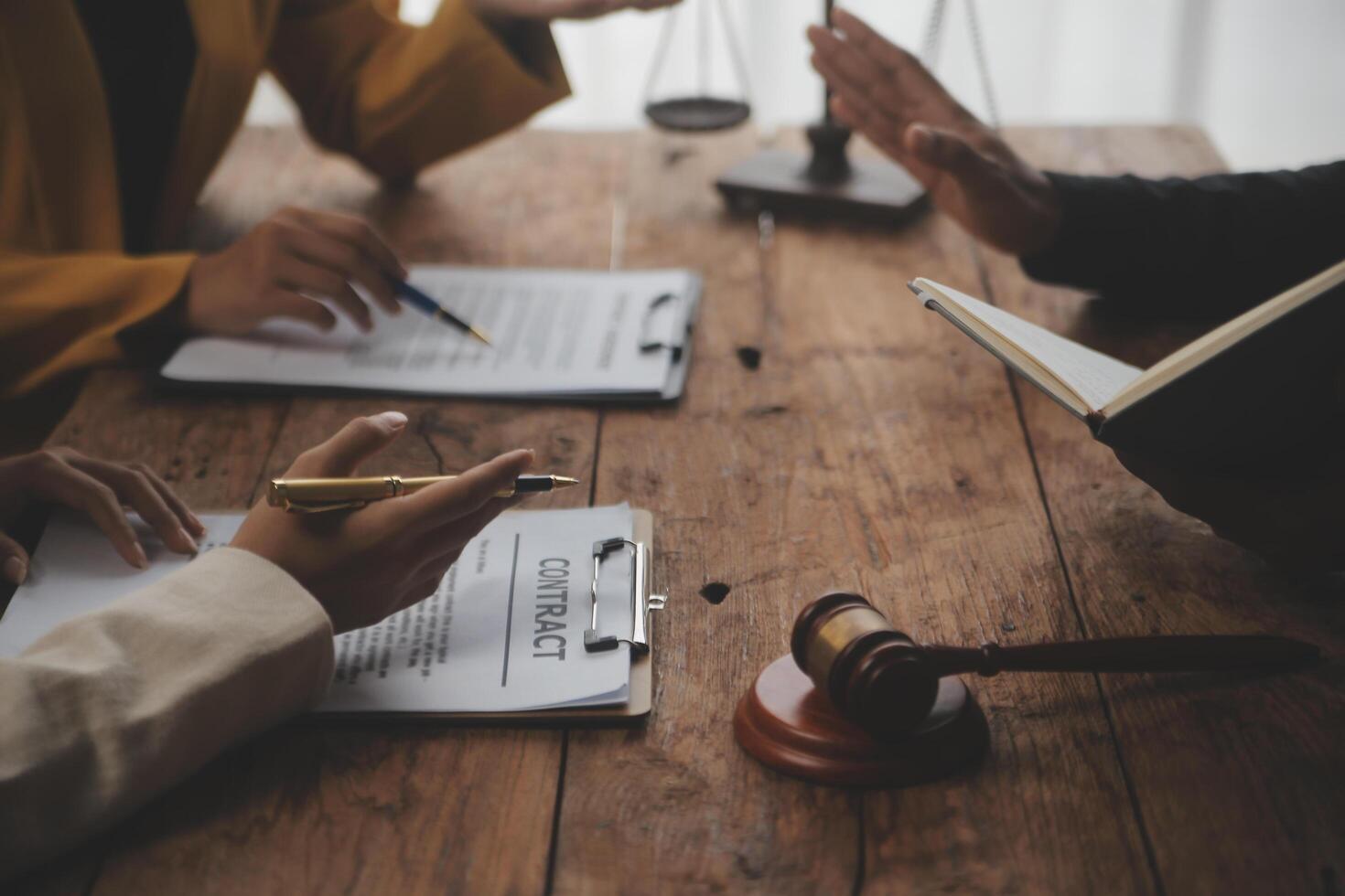 Business and lawyers discussing contract papers with brass scale on desk in office. Law, legal services, advice, justice and law concept picture with film grain effect photo